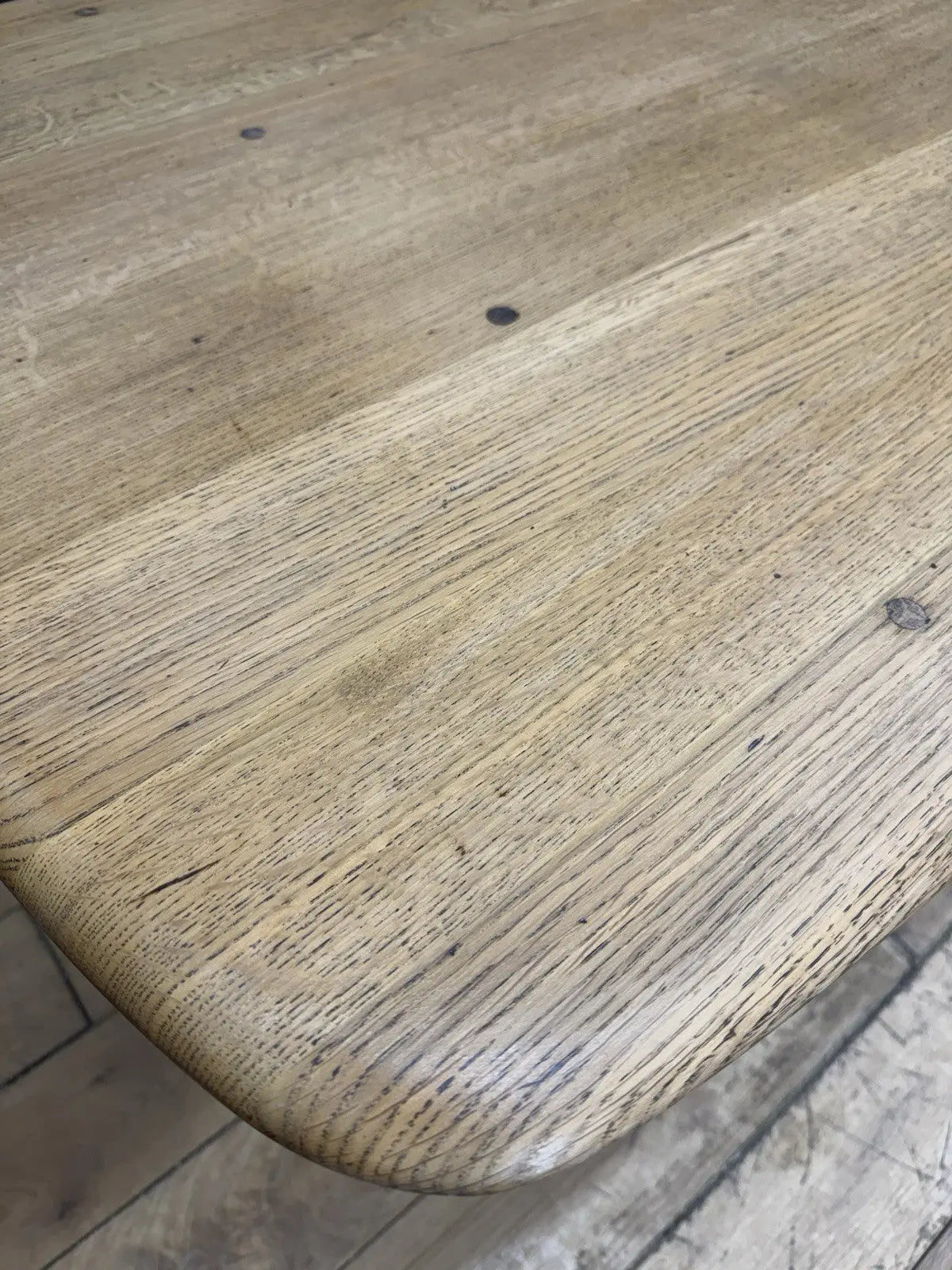 Ercol brown oak refectory dining table with natural wood grain and traditional trestle base.