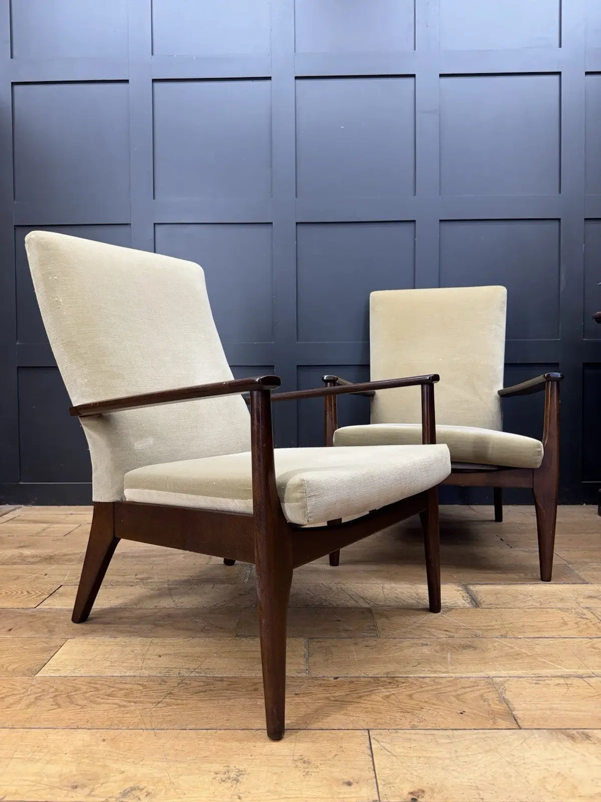 Parker Knoll cream armchairs with sculpted wooden arms and tapered legs, vintage mid-century design.