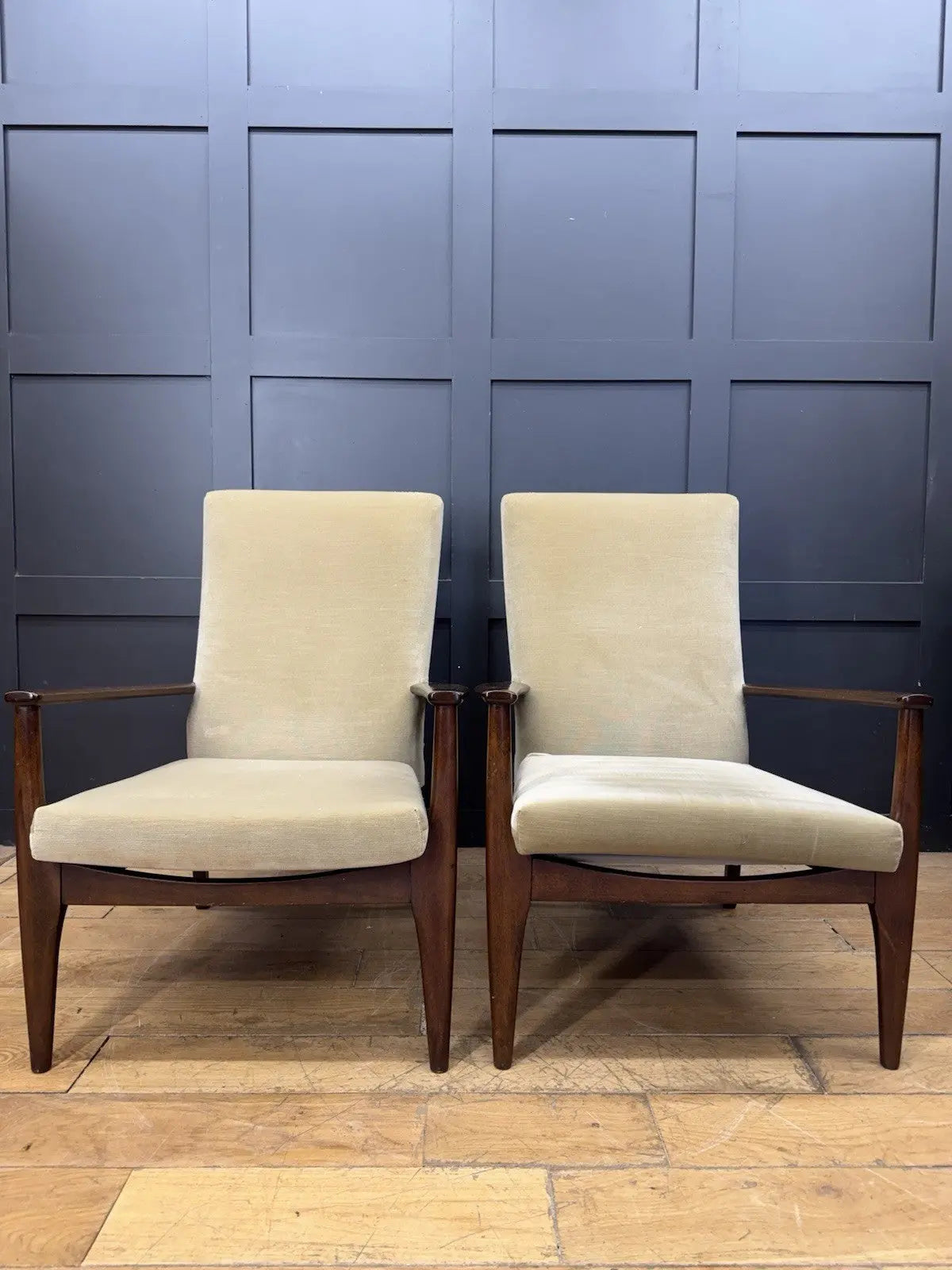 Parker Knoll cream armchairs with sculpted wooden arms and tapered legs, vintage mid-century design.