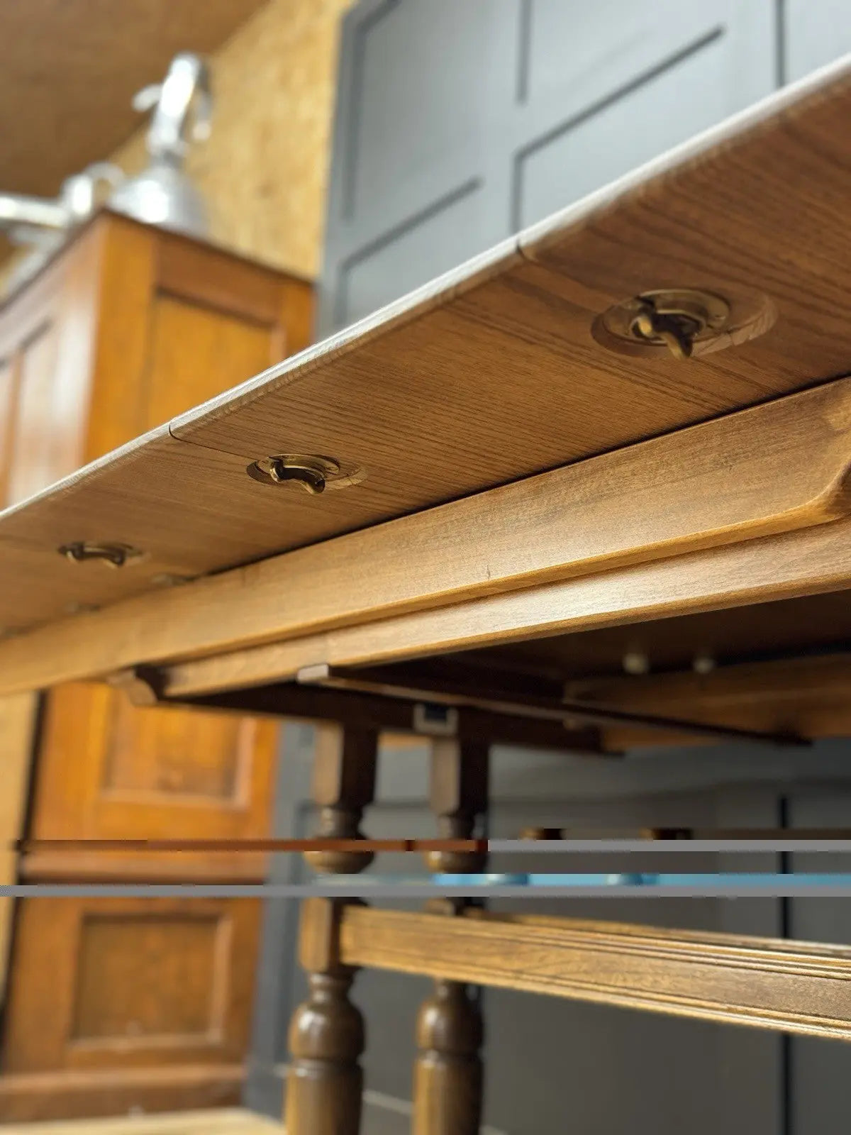Ercol brown extending dining table with solid elm top and three individual extension leaves.