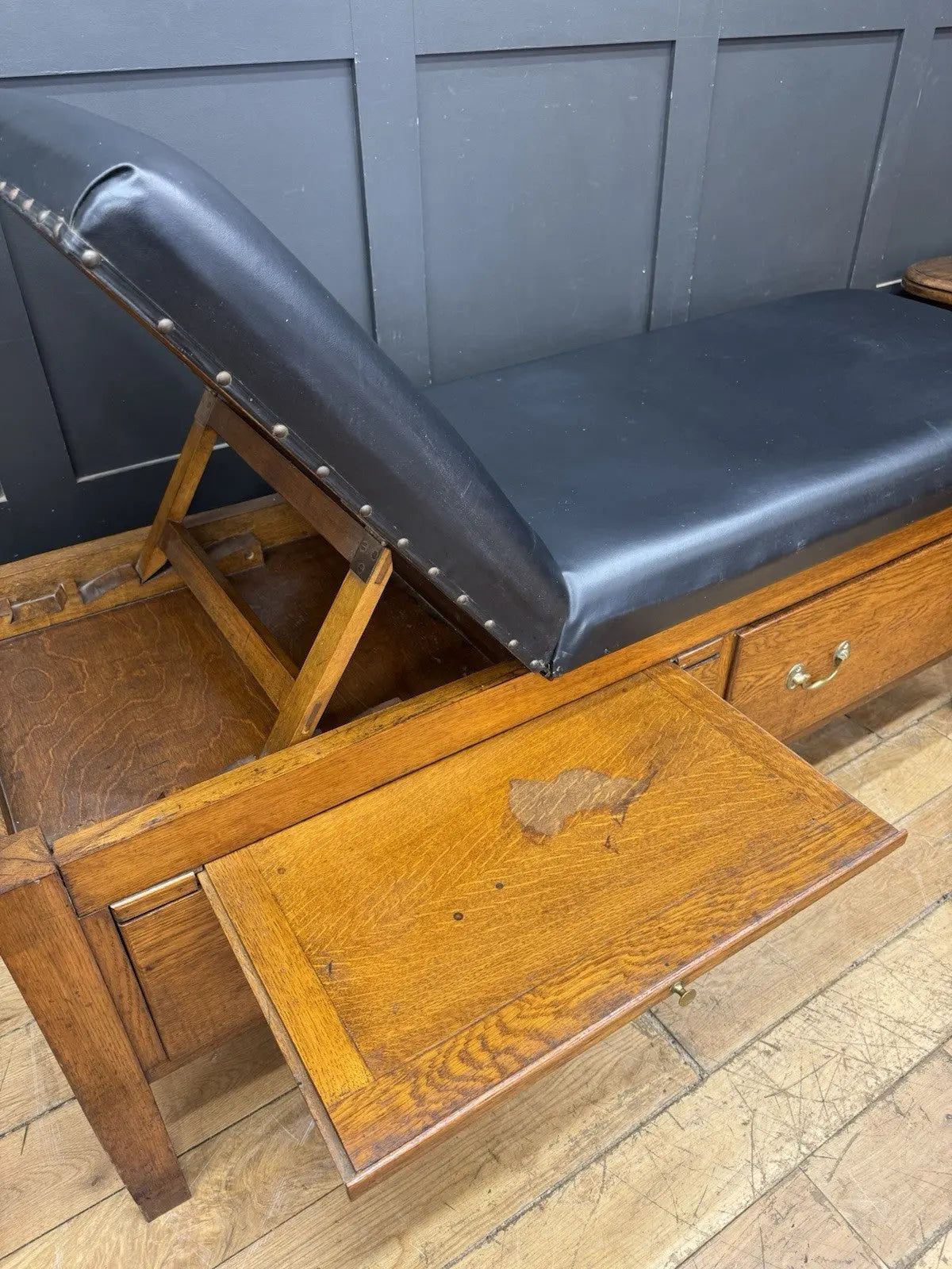 Harris black chaise longue with oak frame, padded Rexine seat, and original maker's plaque.
