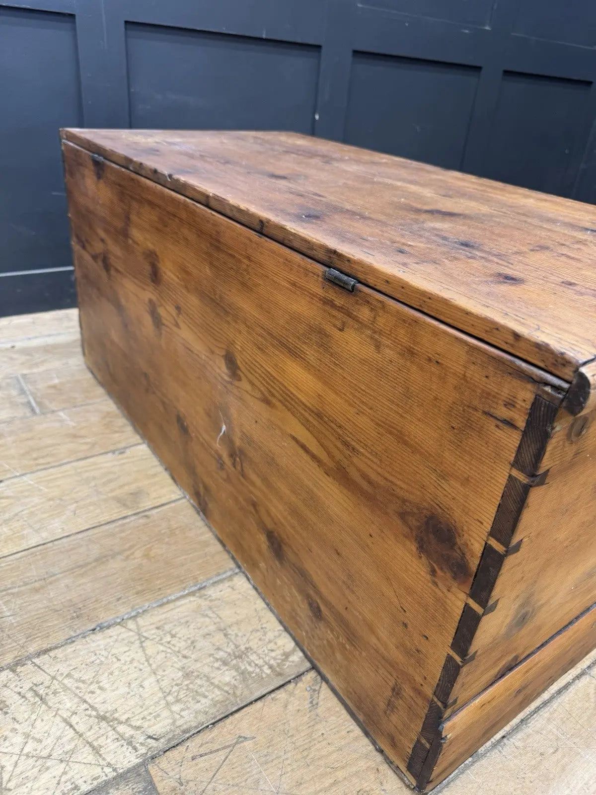 Antique pine hope chest with honey-coloured finish, iron handles, and dovetailed joints.