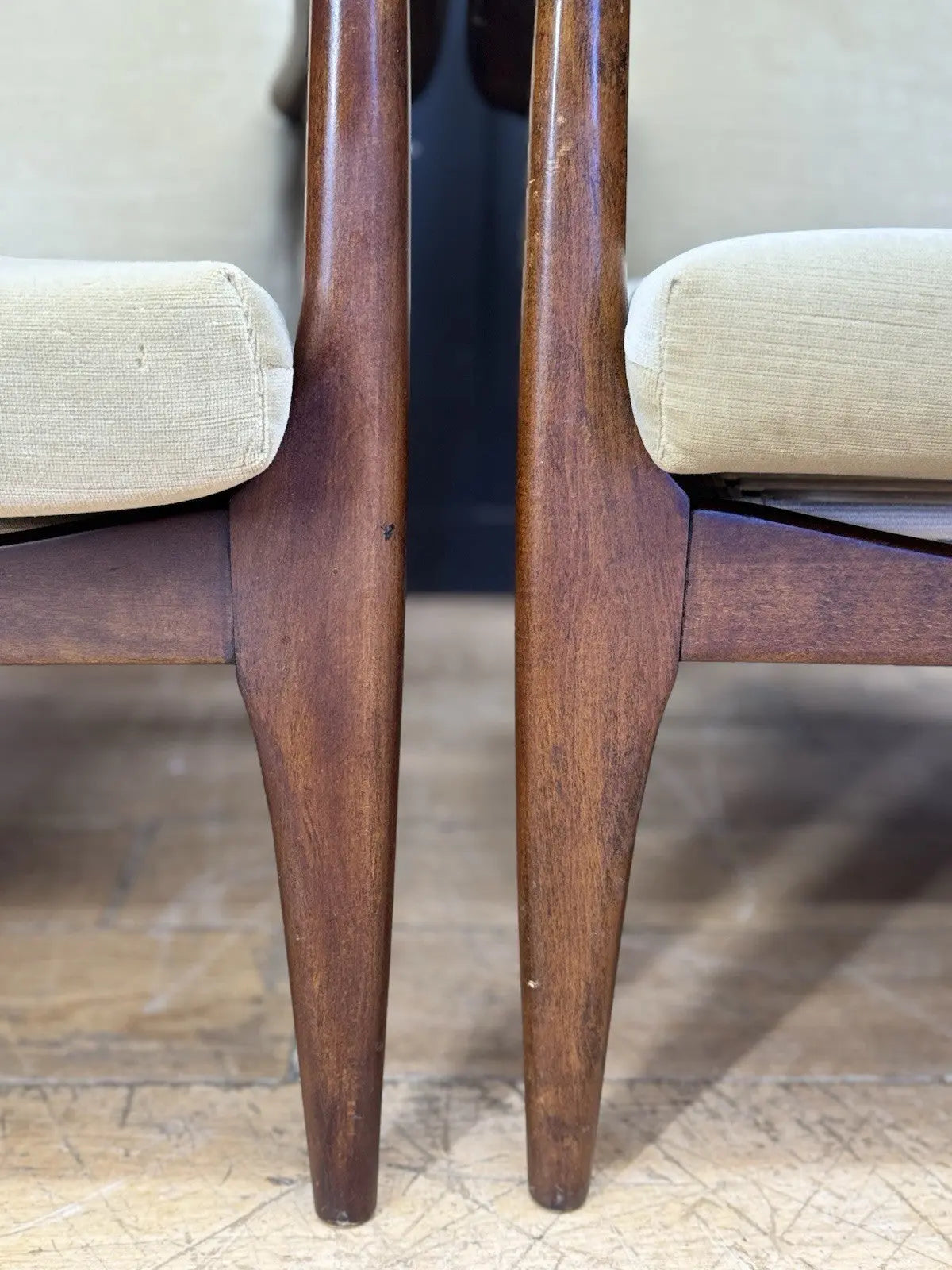 Parker Knoll cream armchairs with sculpted wooden arms and tapered legs, vintage mid-century design.
