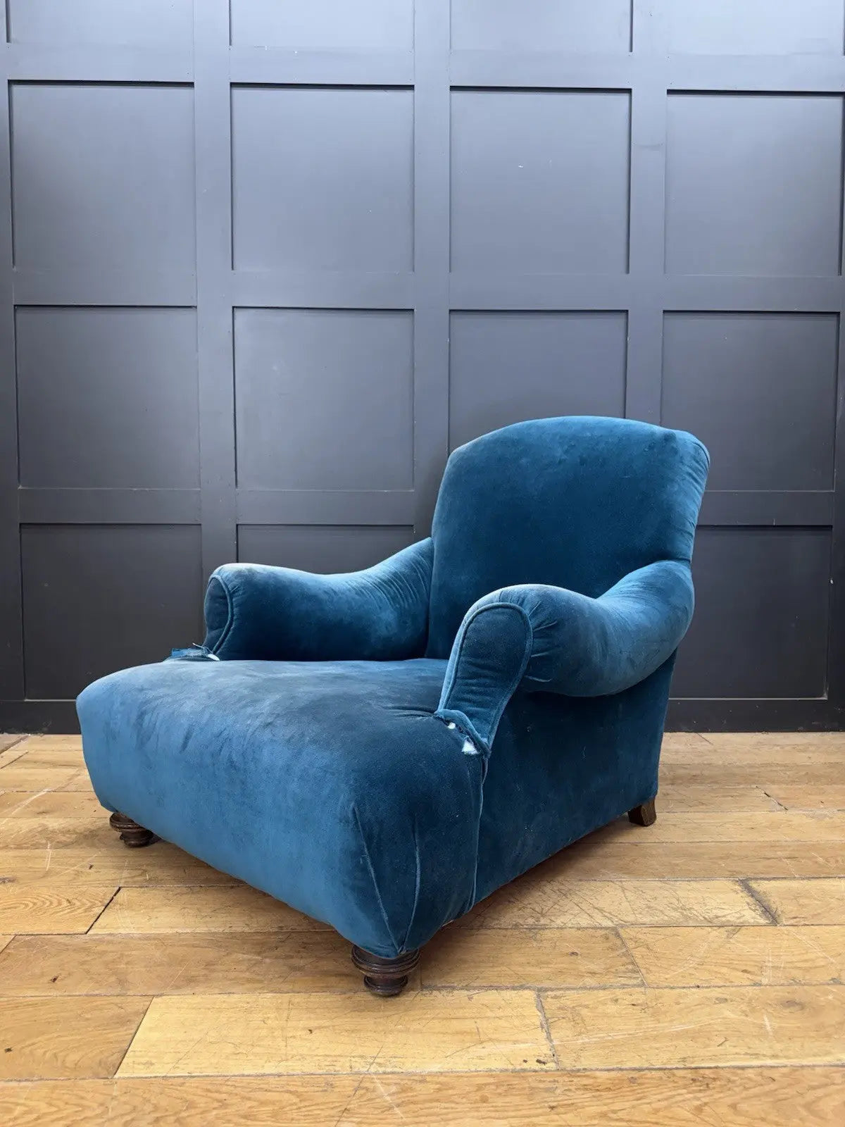 Antique blue velvet armchair with curved back, scroll arms, and stamped 'P' on frame.
