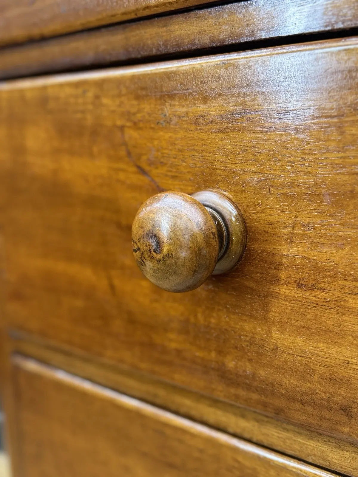 Antique brown mahogany chest of drawers with rounded corners and wooden knob handles.