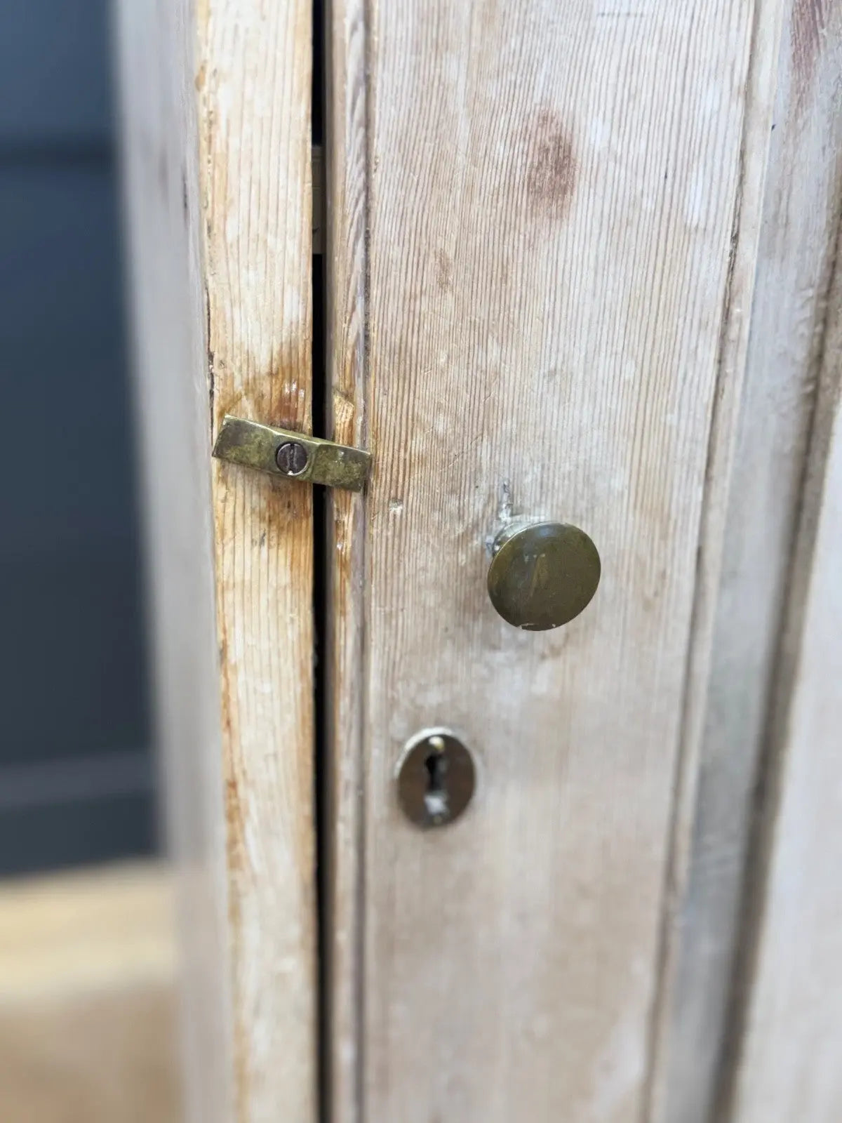 Antique beige pine cupboard with stripped finish, brass knob, and painted interior.