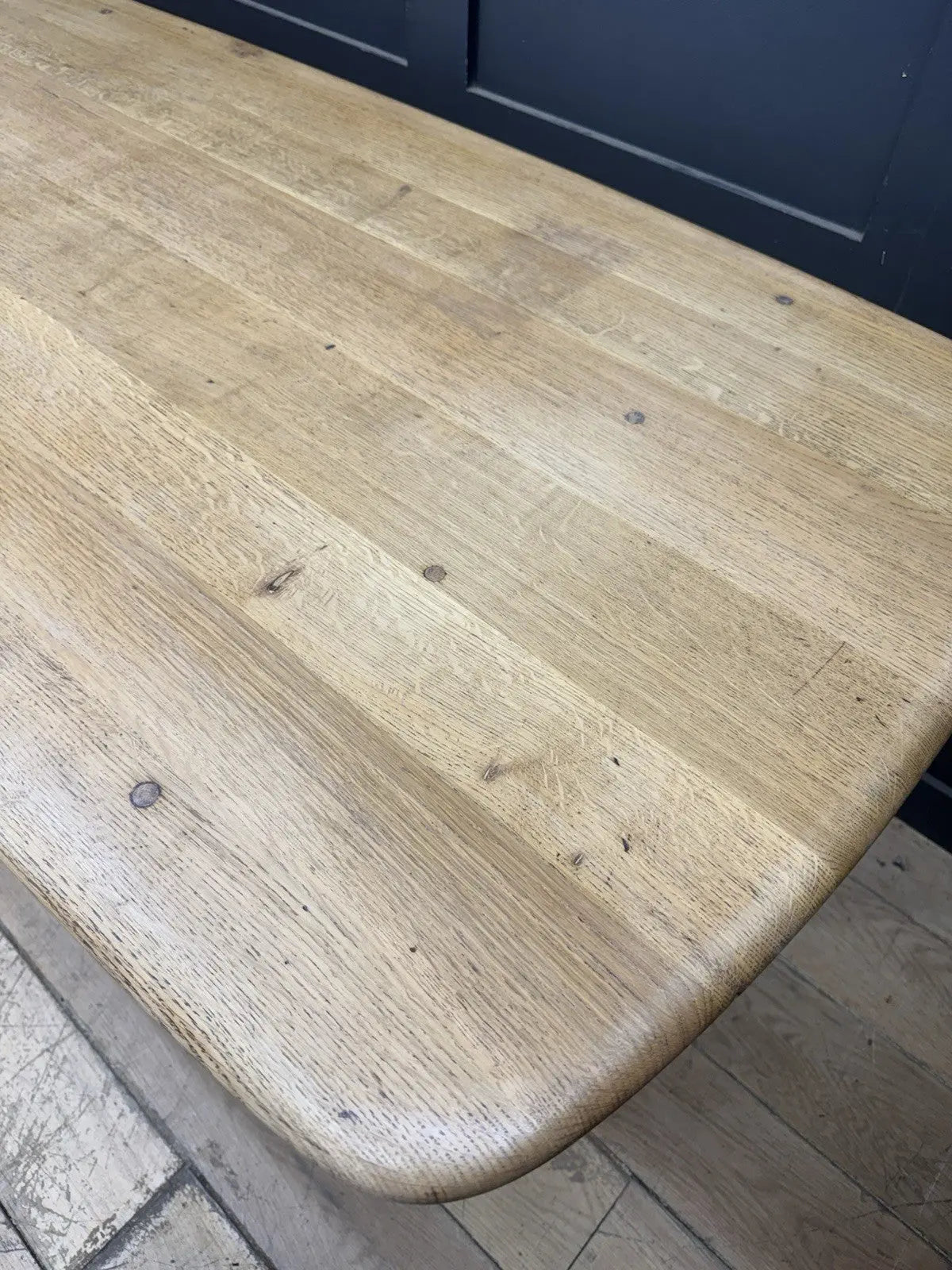 Ercol brown oak refectory dining table with natural wood grain and traditional trestle base.
