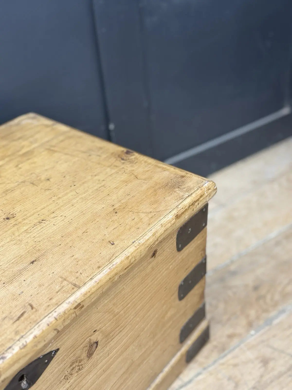 Vintage pine coffee table brown with natural grain and dark metal corner brackets.