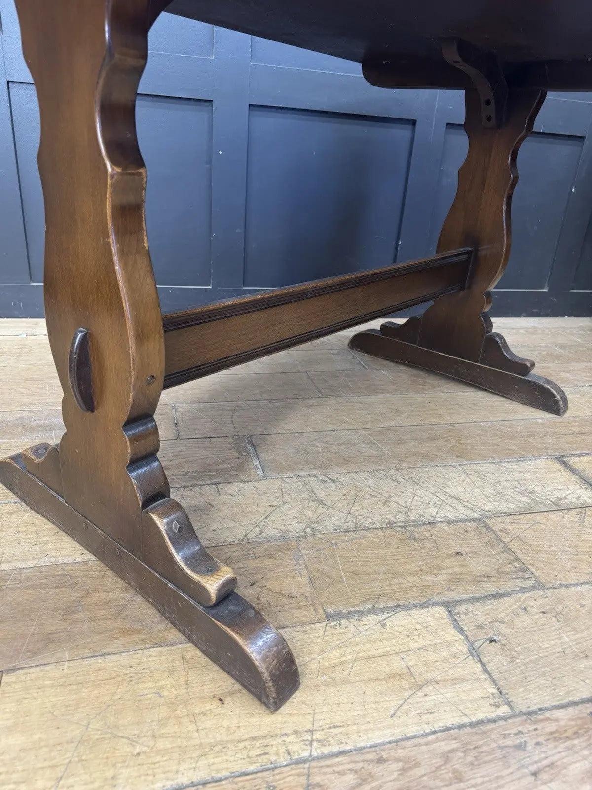 Ercol brown oak refectory dining table with natural wood grain and traditional trestle base.