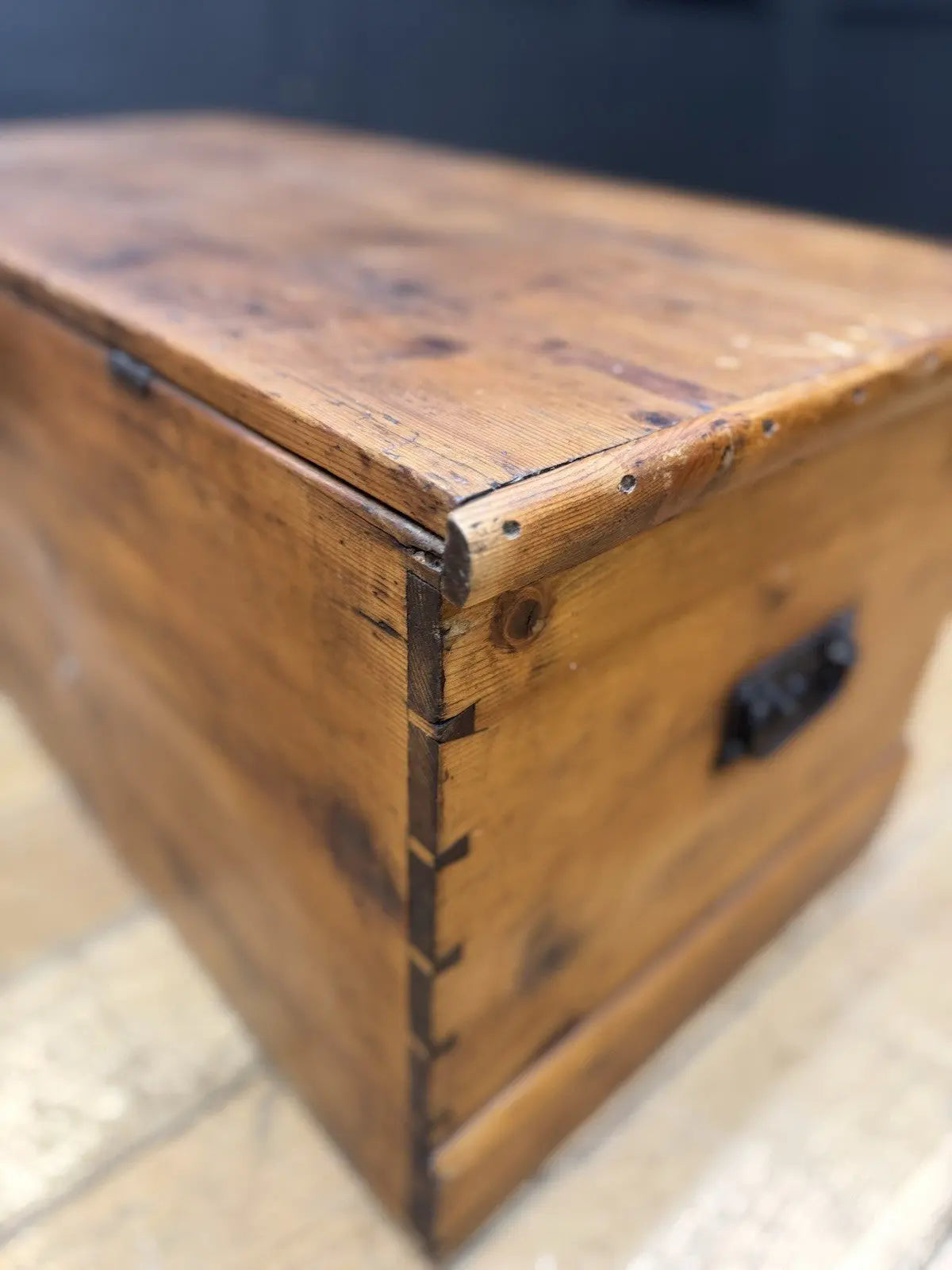 Antique pine hope chest with honey-coloured finish, iron handles, and dovetailed joints.