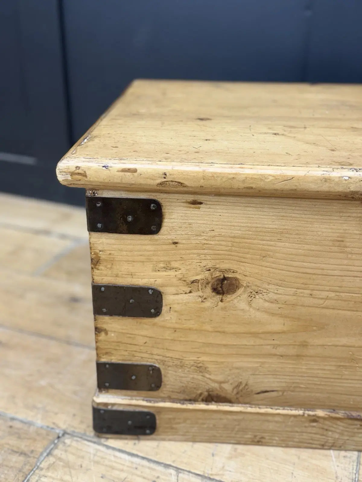 Vintage pine coffee table brown with natural grain and dark metal corner brackets.