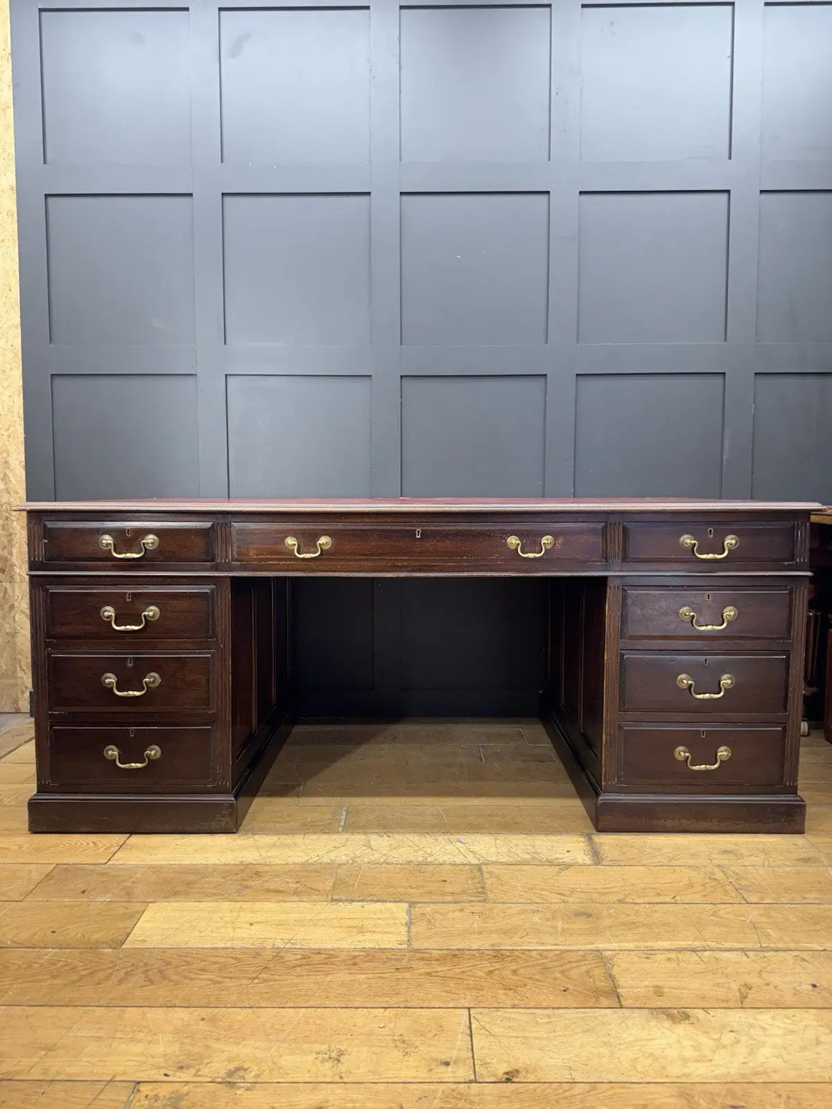 Twin antique mahogany writing desk with red leather top and brass swan-neck handles.