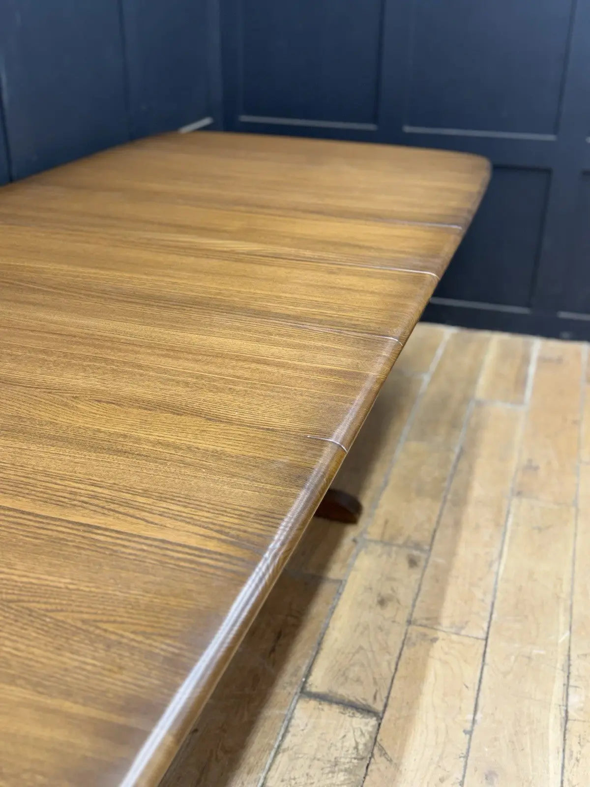 Ercol brown extending dining table with solid elm top and three individual extension leaves.