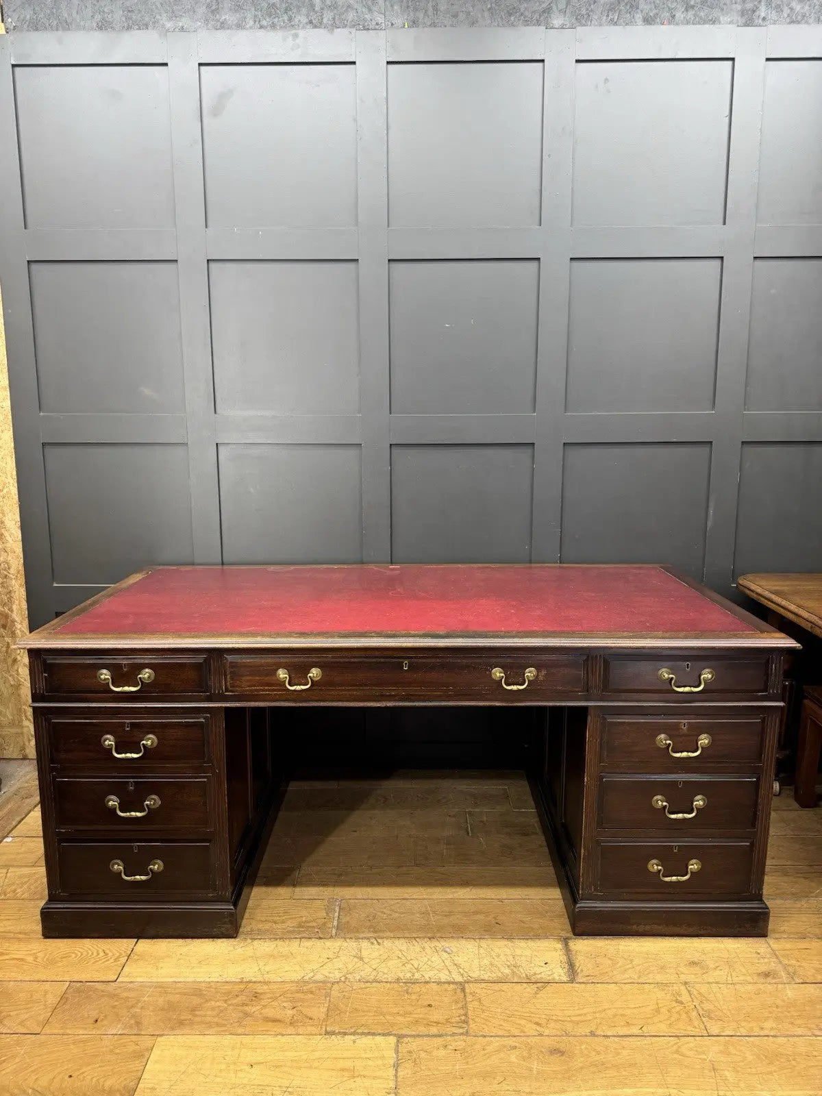 Twin antique mahogany writing desk with red leather top and brass swan-neck handles.