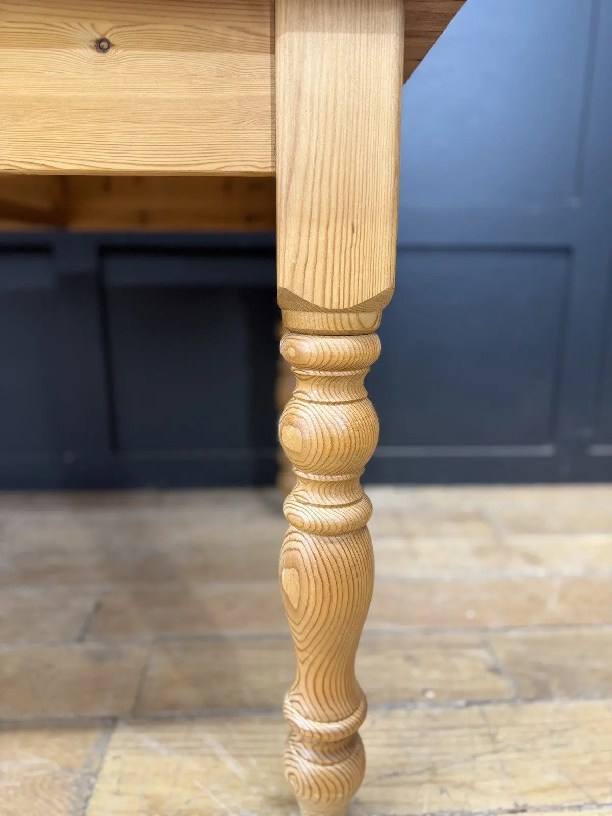 Vintage brown farmhouse dining table with turned legs and central drawer featuring white ceramic knob.