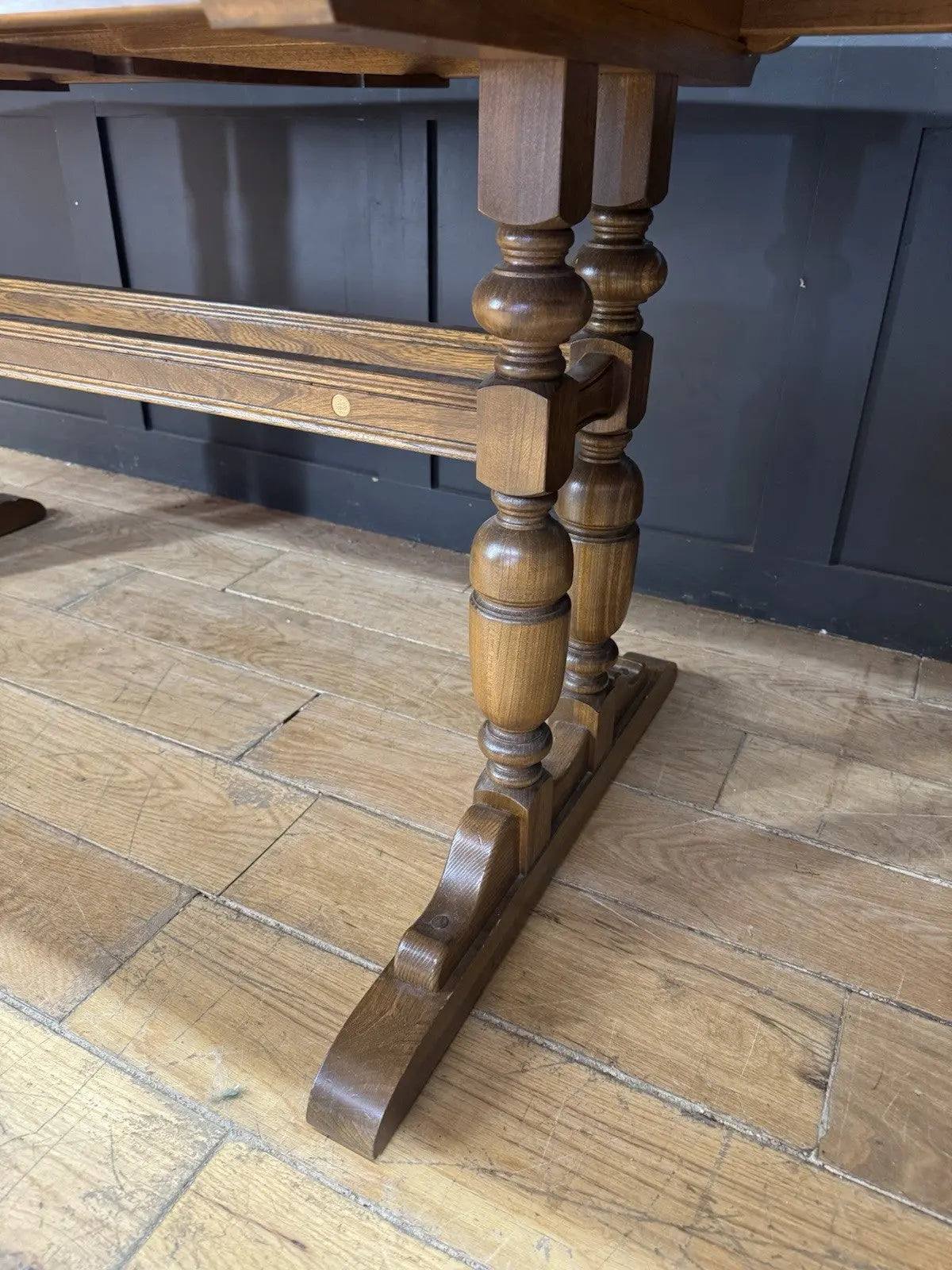 Ercol brown extending dining table with solid elm top and three individual extension leaves.