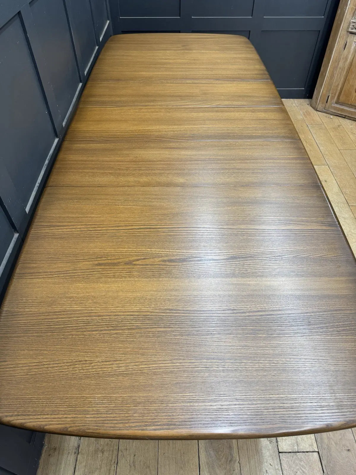 Ercol brown extending dining table with solid elm top and three individual extension leaves.