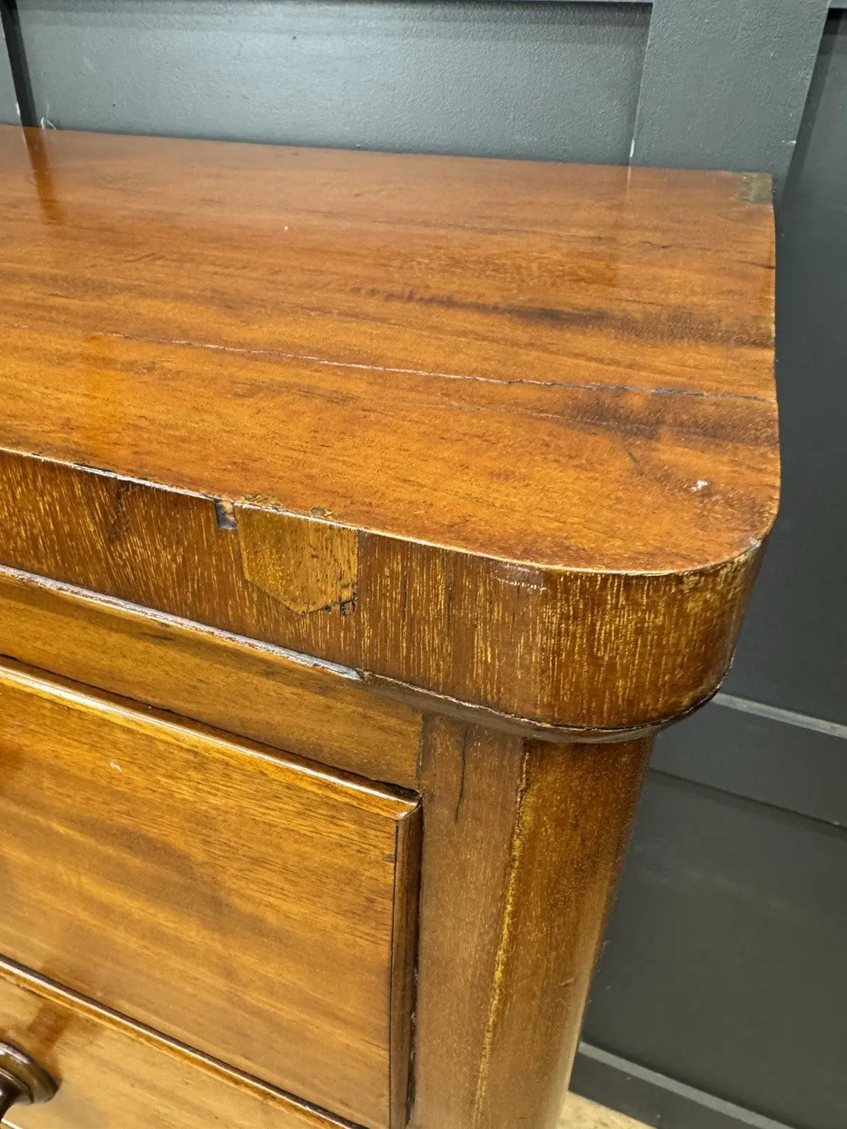Antique brown mahogany chest of drawers with rounded corners and wooden knob handles.