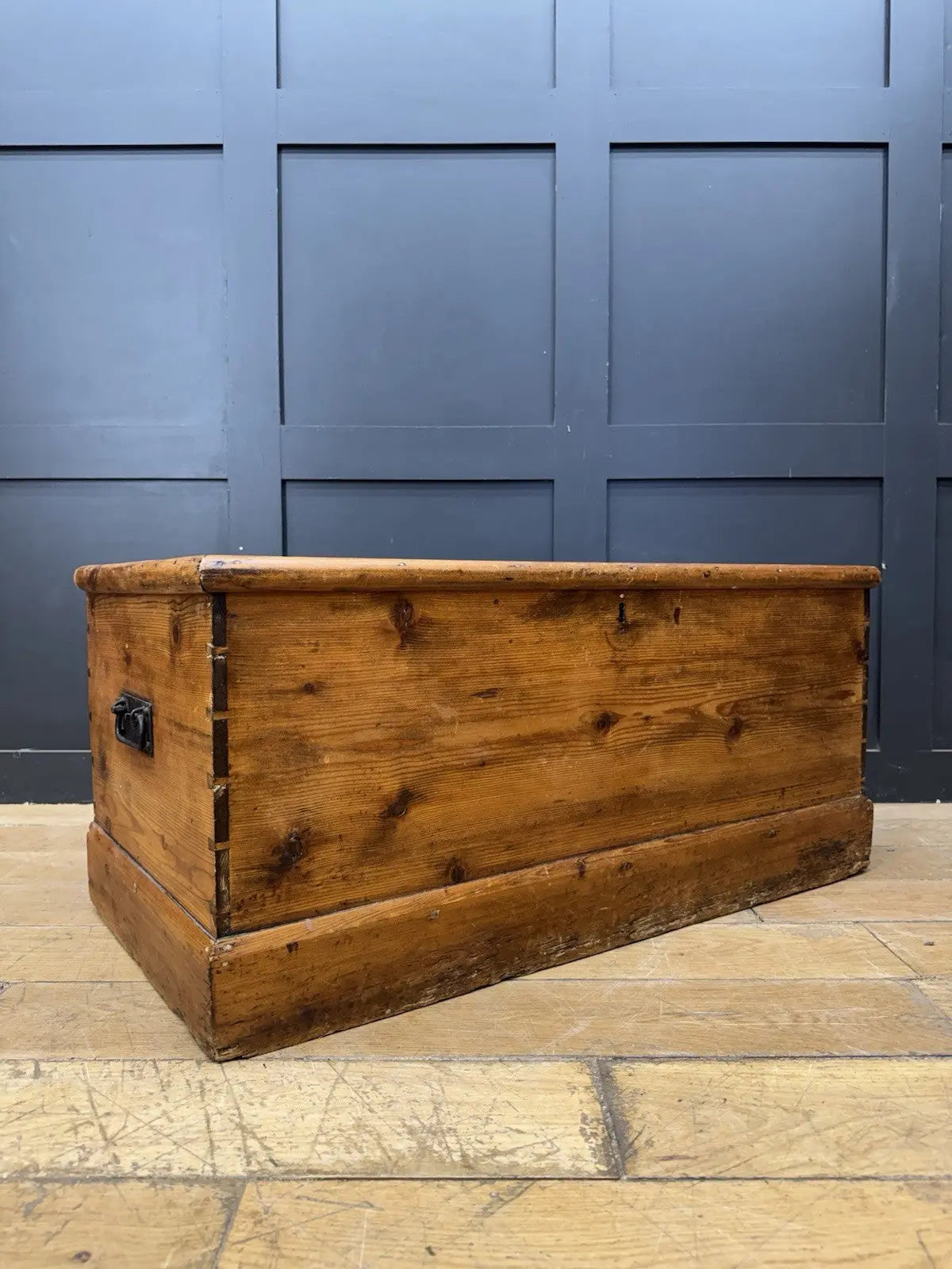 Antique pine hope chest with honey-coloured finish, iron handles, and dovetailed joints.