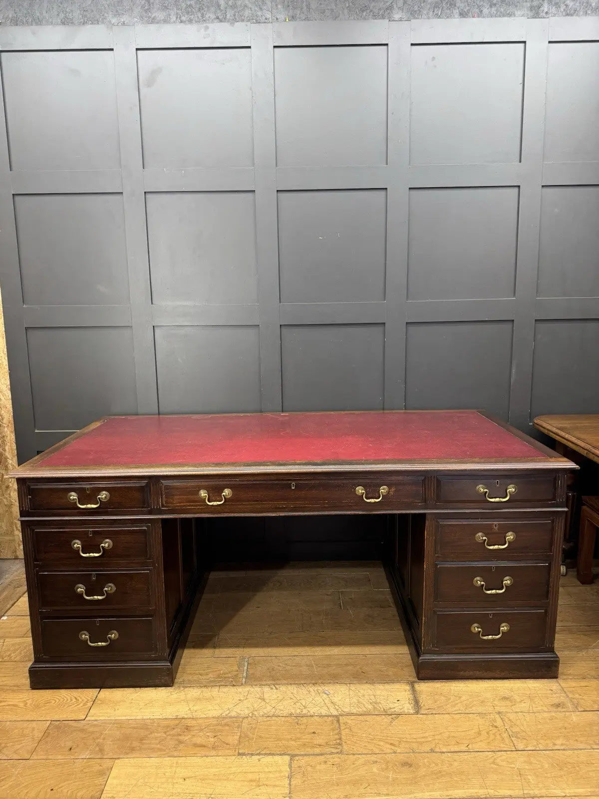 Twin antique mahogany writing desk with red leather top and brass swan-neck handles.