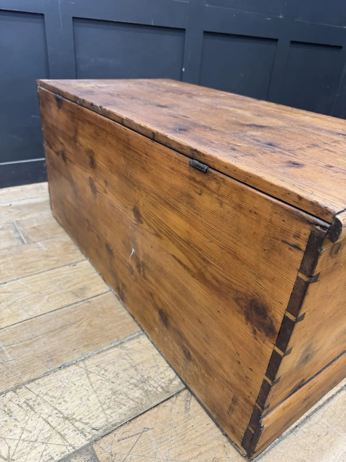 Antique pine hope chest with honey-coloured finish, iron handles, and dovetailed joints.