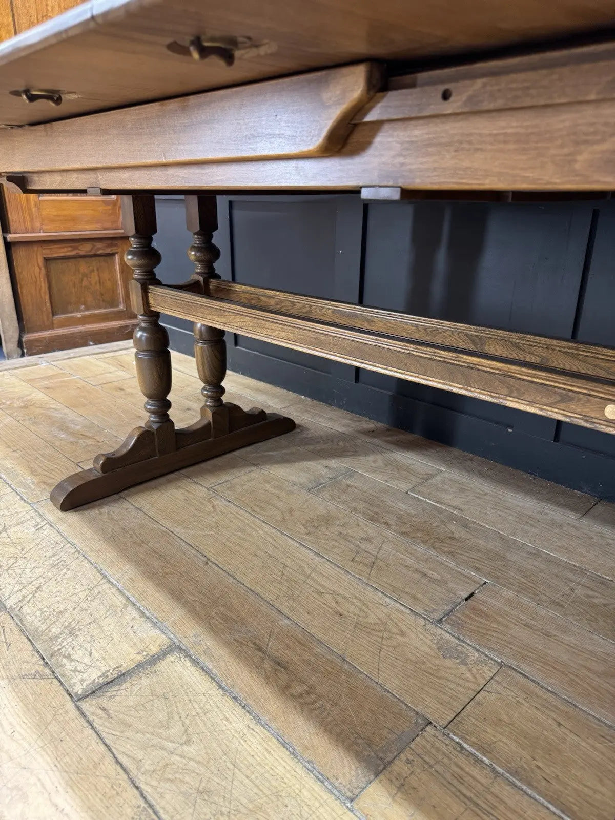 Ercol brown extending dining table with solid elm top and three individual extension leaves.