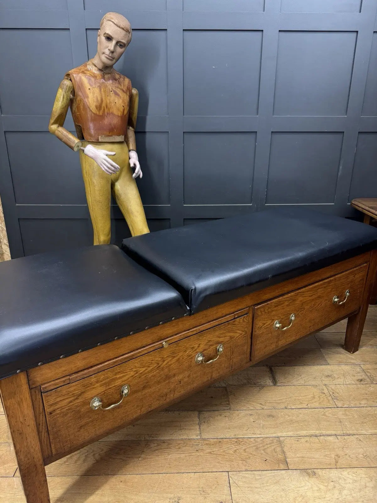 Harris black chaise longue with oak frame, padded Rexine seat, and original maker's plaque.