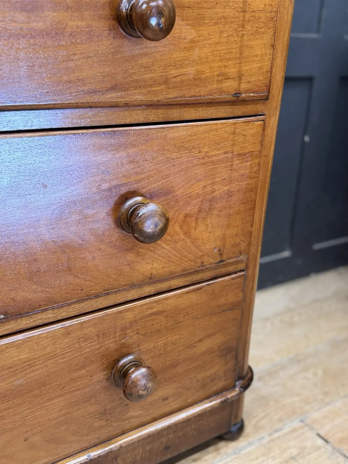 Antique brown mahogany chest of drawers with rounded corners and wooden knob handles.