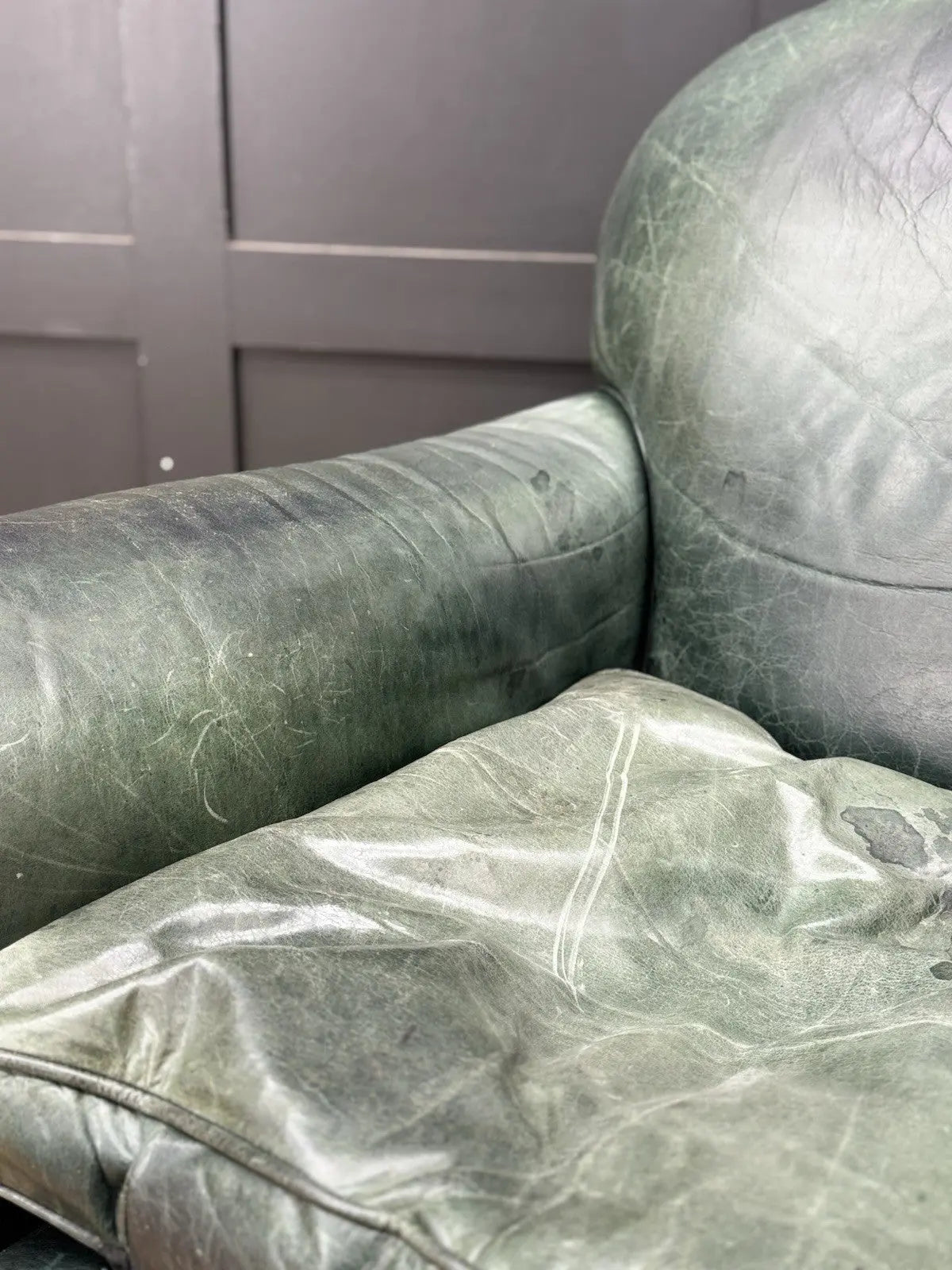 Tetrad green leather armchair with gathered detailing, twisted piping, and original manufacturer's label.
