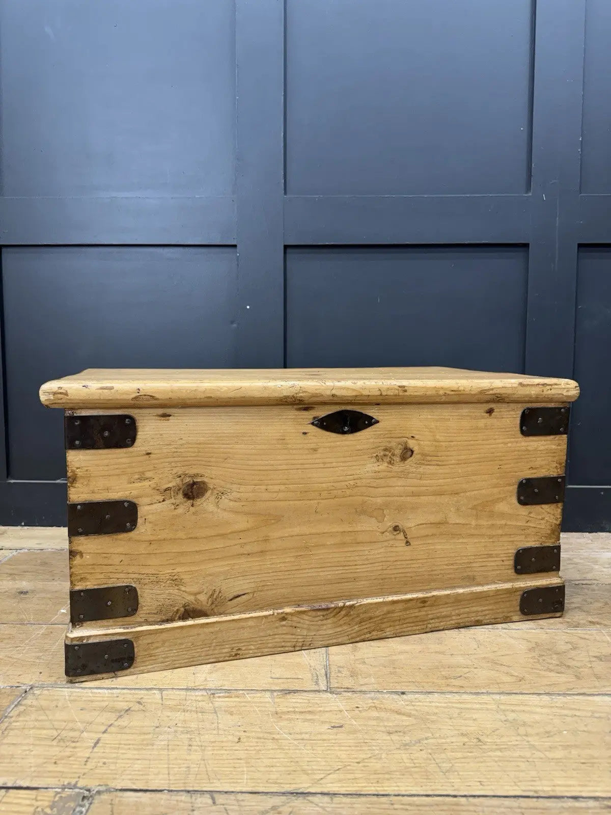 Vintage pine coffee table brown with natural grain and dark metal corner brackets.