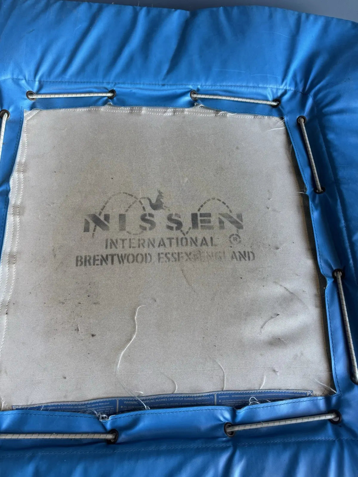 Rebounder black and blue gymnastics trampette with Nissen International logo and woven jumping bed.
