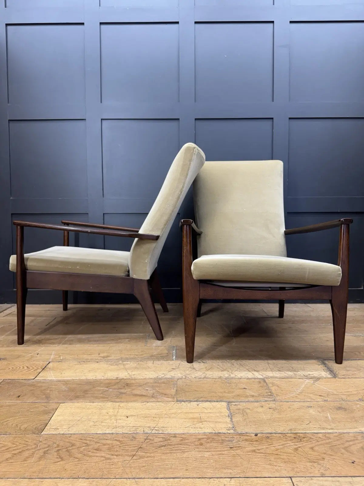 Parker Knoll cream armchairs with sculpted wooden arms and tapered legs, vintage mid-century design.