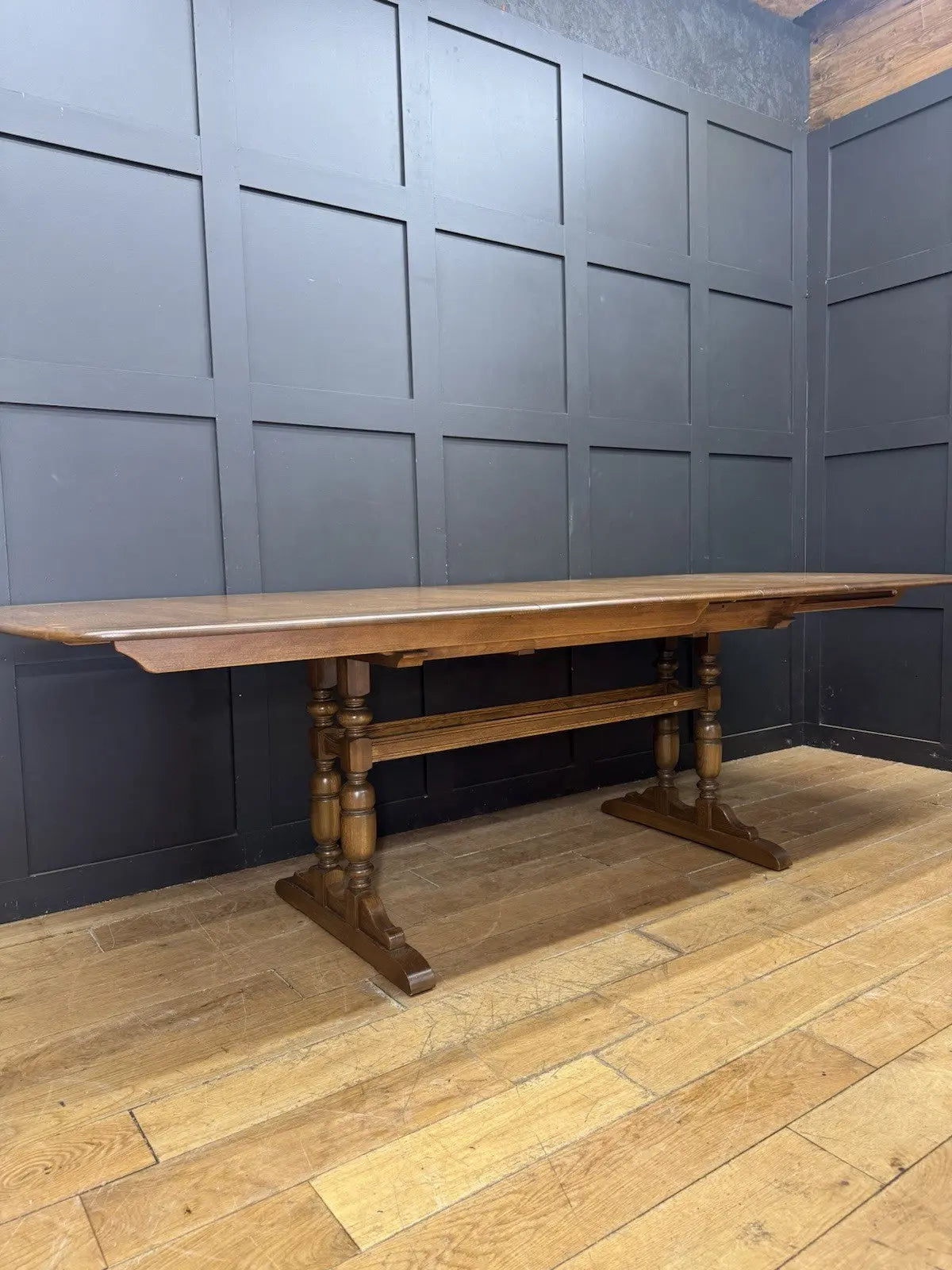 Ercol brown extending dining table with solid elm top and three individual extension leaves.