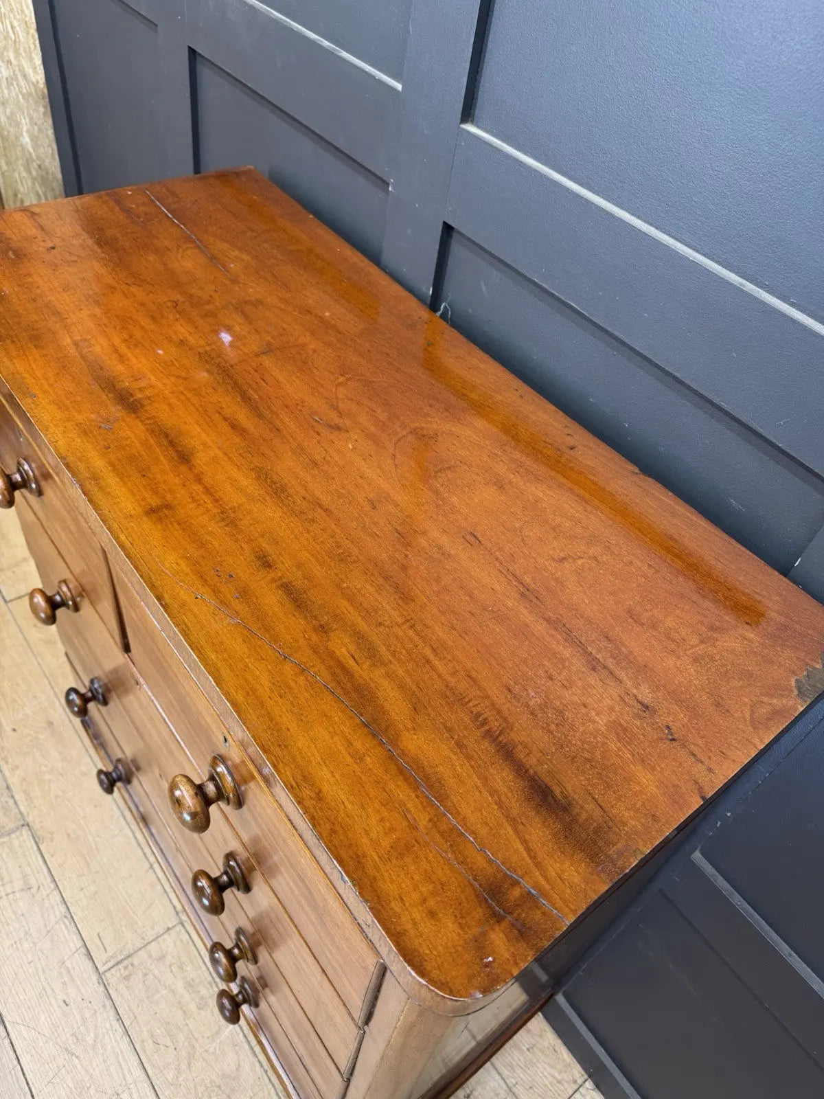 Antique brown mahogany chest of drawers with rounded corners and wooden knob handles.
