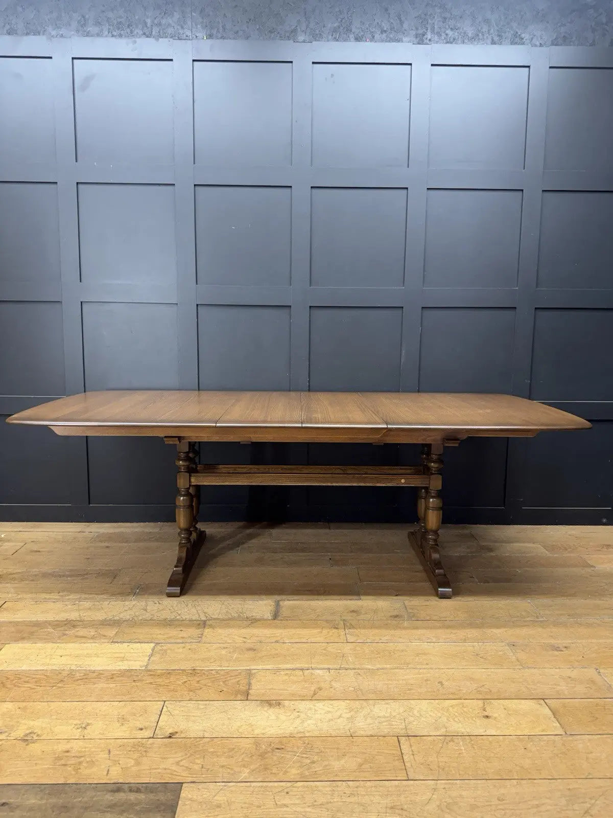 Ercol brown extending dining table with solid elm top and three individual extension leaves.