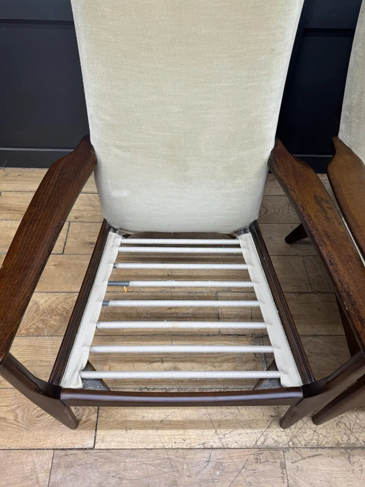 Parker Knoll cream armchairs with sculpted wooden arms and tapered legs, vintage mid-century design.