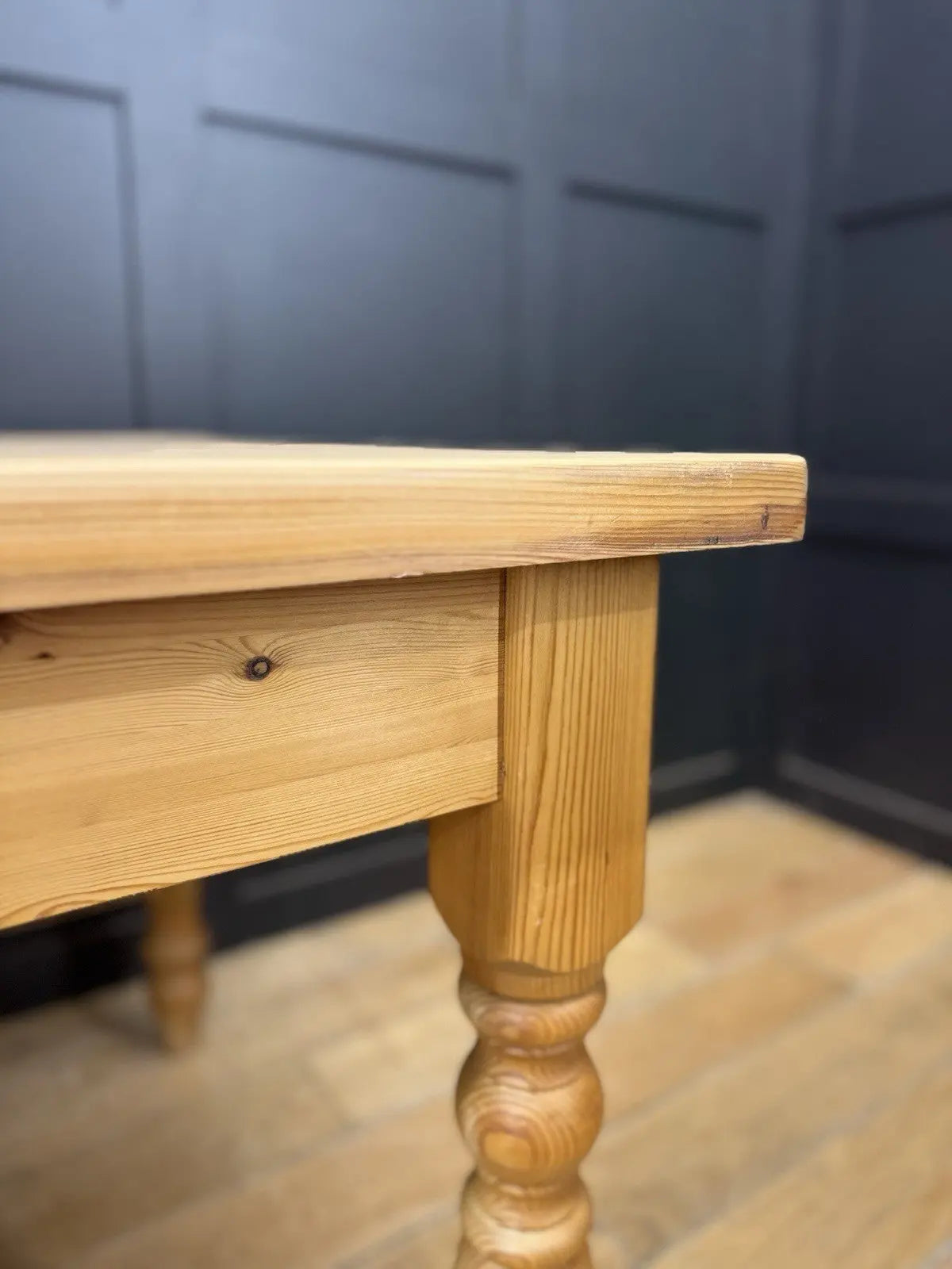 Vintage brown farmhouse dining table with turned legs and central drawer featuring white ceramic knob.