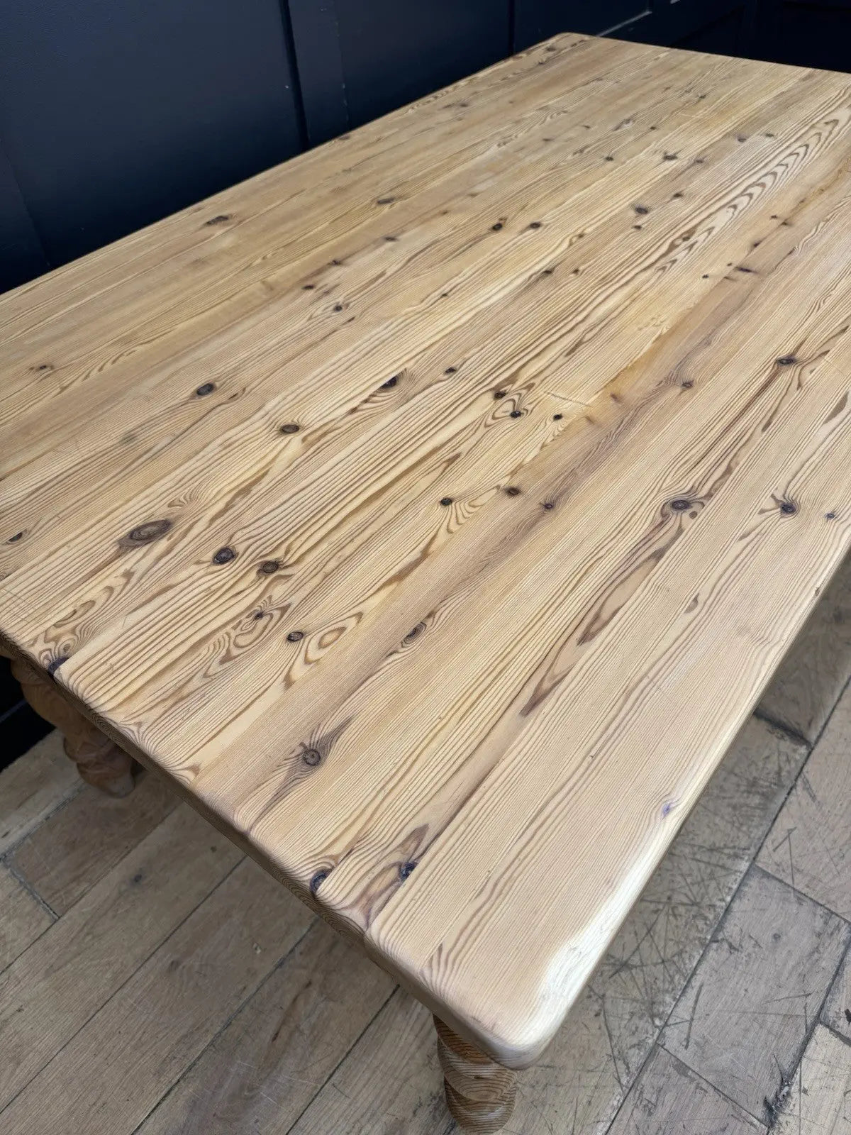 Vintage brown farmhouse dining table with turned legs and central drawer featuring white ceramic knob.