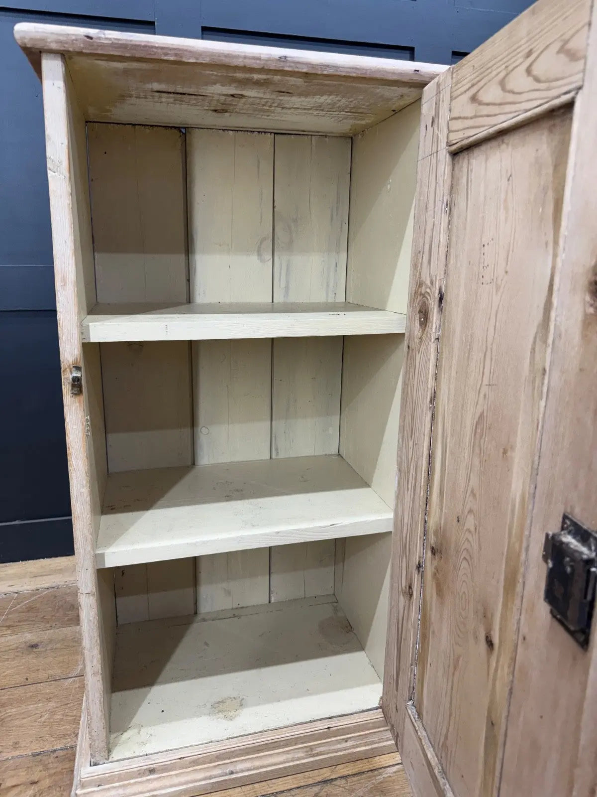 Antique beige pine cupboard with stripped finish, brass knob, and painted interior.