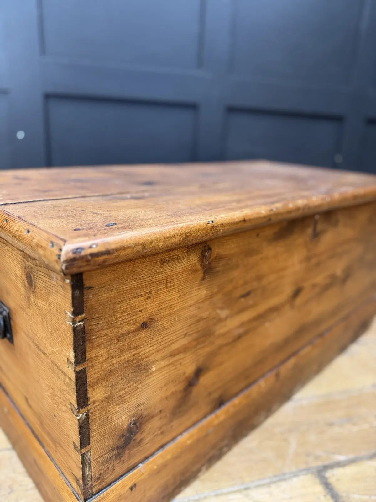 Antique pine hope chest with honey-coloured finish, iron handles, and dovetailed joints.