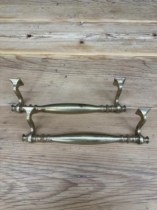 Vintage brass door pull handles with elegant spindle design and warm patina finish.