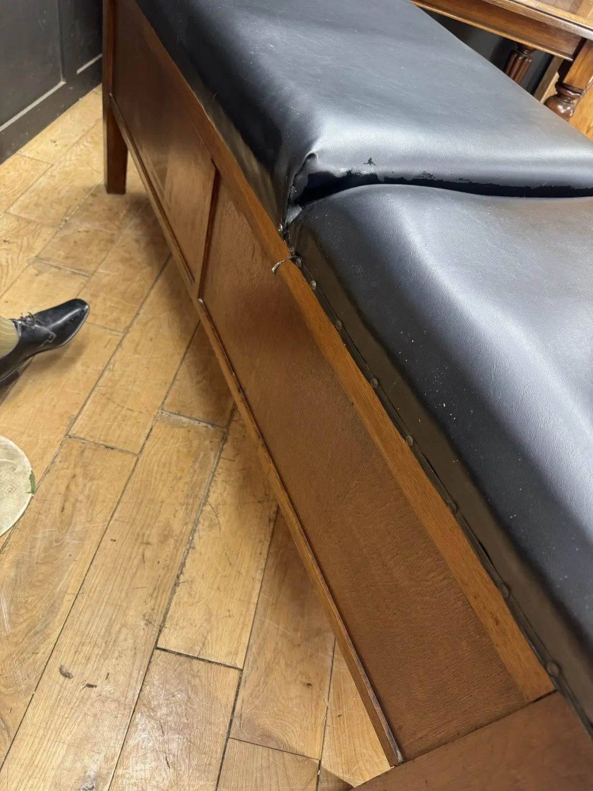 Harris black chaise longue with oak frame, padded Rexine seat, and original maker's plaque.