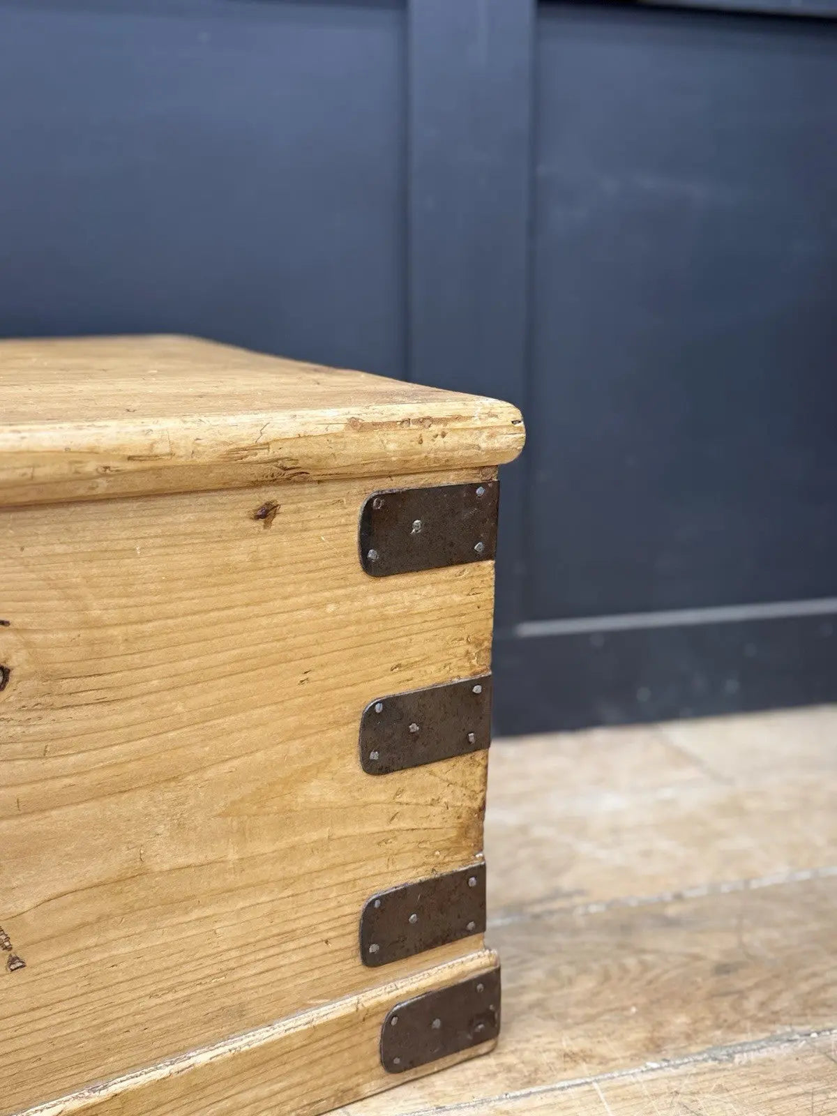 Vintage pine coffee table brown with natural grain and dark metal corner brackets.