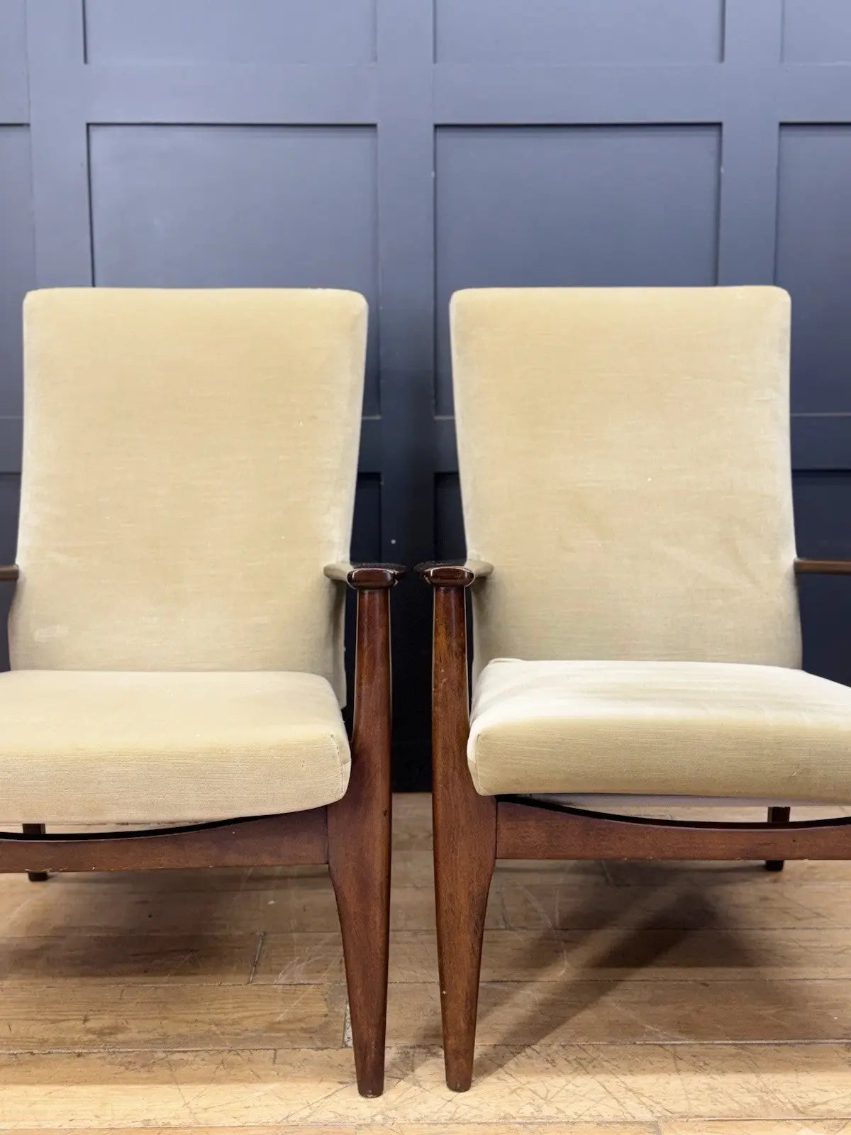 Parker Knoll cream armchairs with sculpted wooden arms and tapered legs, vintage mid-century design.