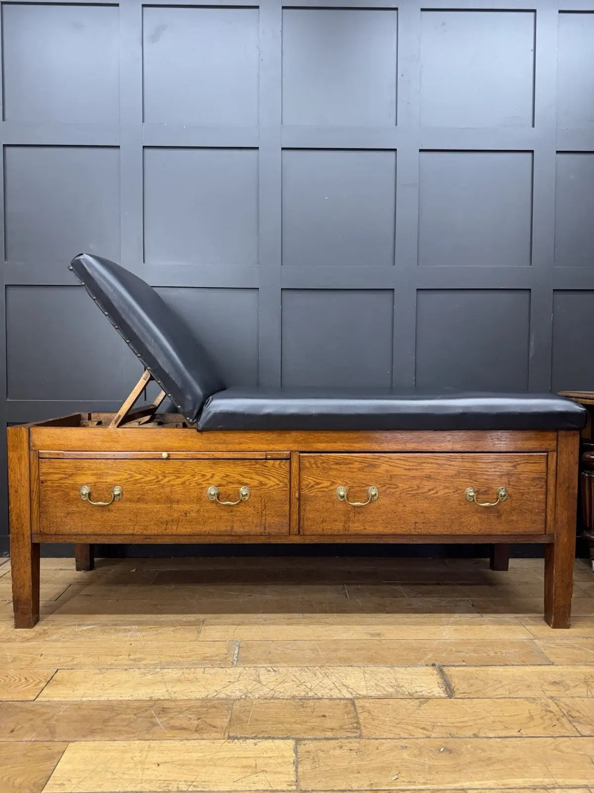 Harris black chaise longue with oak frame, padded Rexine seat, and original maker's plaque.