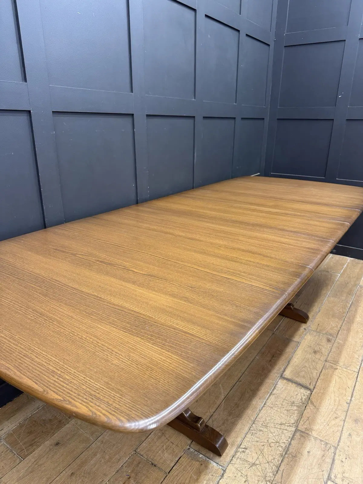 Ercol brown extending dining table with solid elm top and three individual extension leaves.