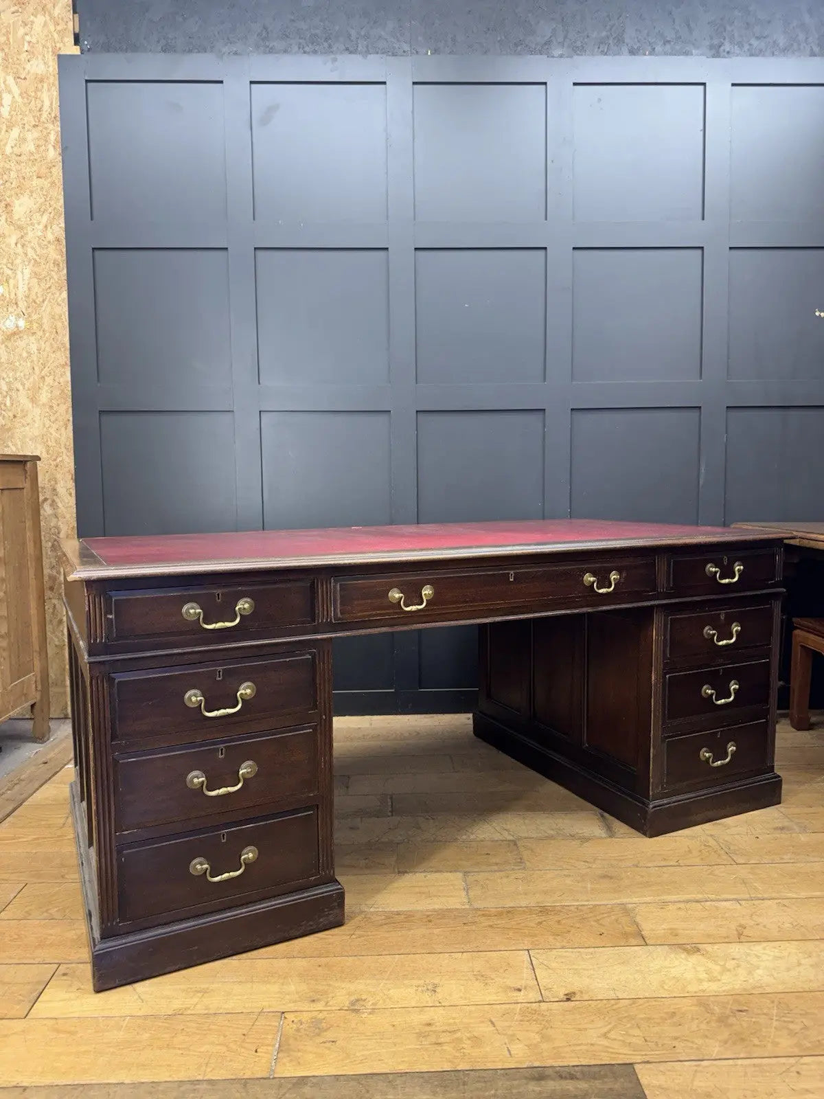 Twin antique mahogany writing desk with red leather top and brass swan-neck handles.