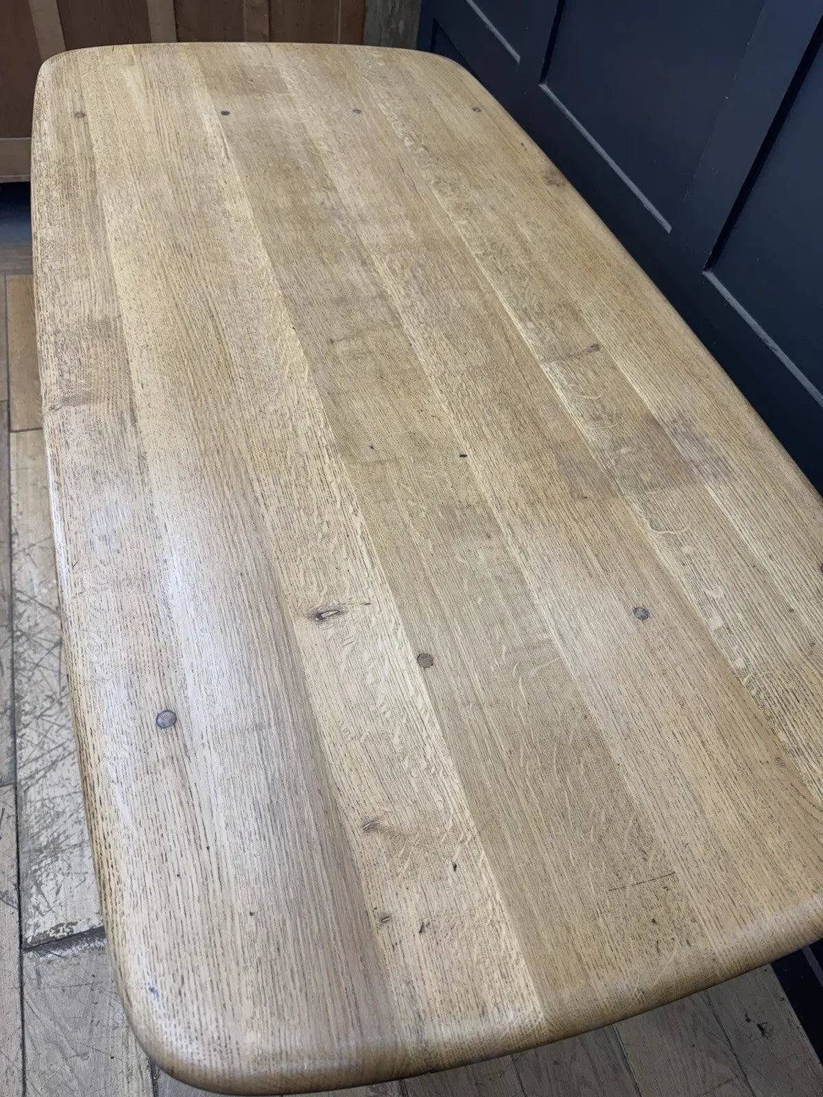 Ercol brown oak refectory dining table with natural wood grain and traditional trestle base.