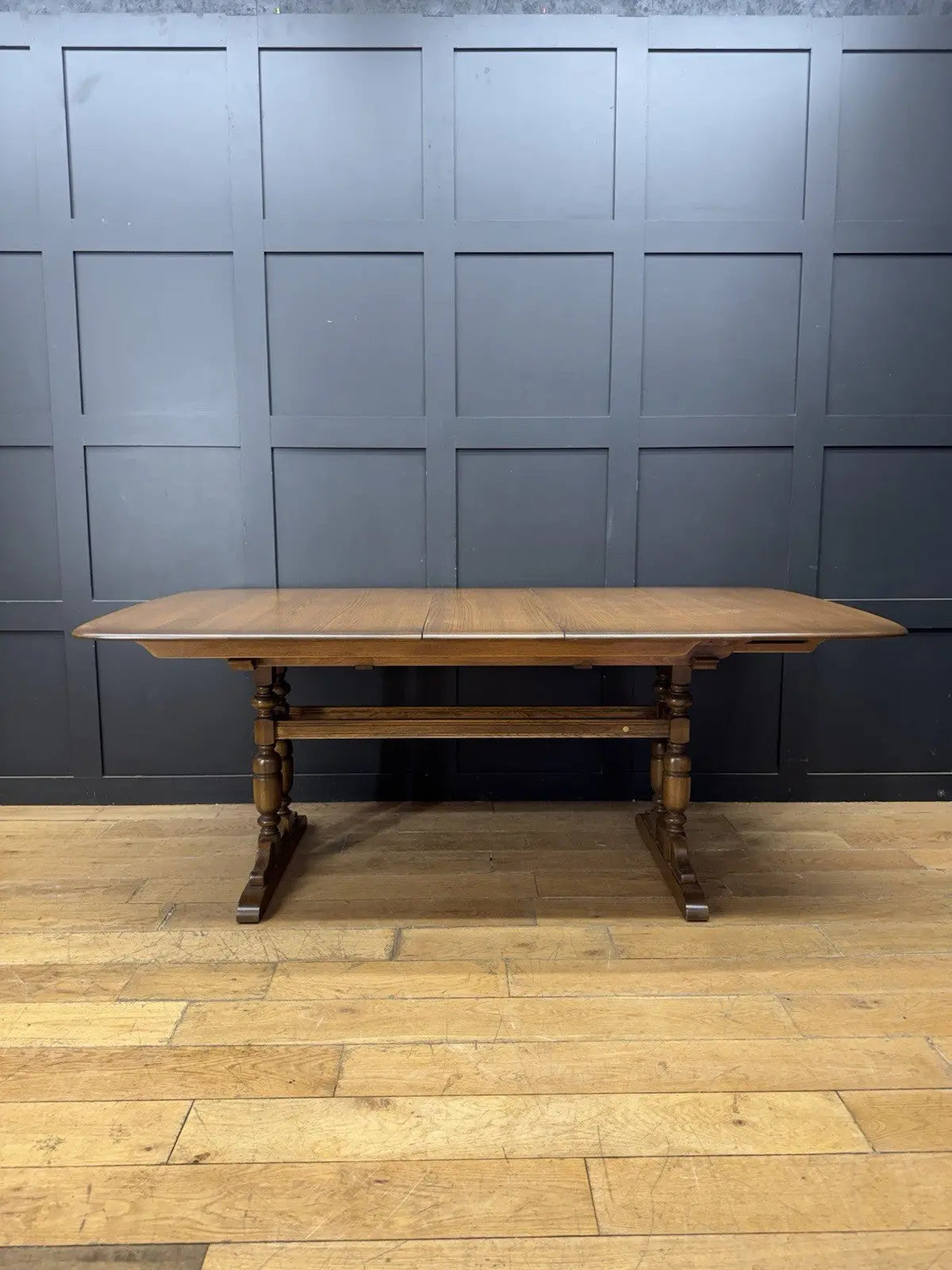 Ercol brown extending dining table with solid elm top and three individual extension leaves.