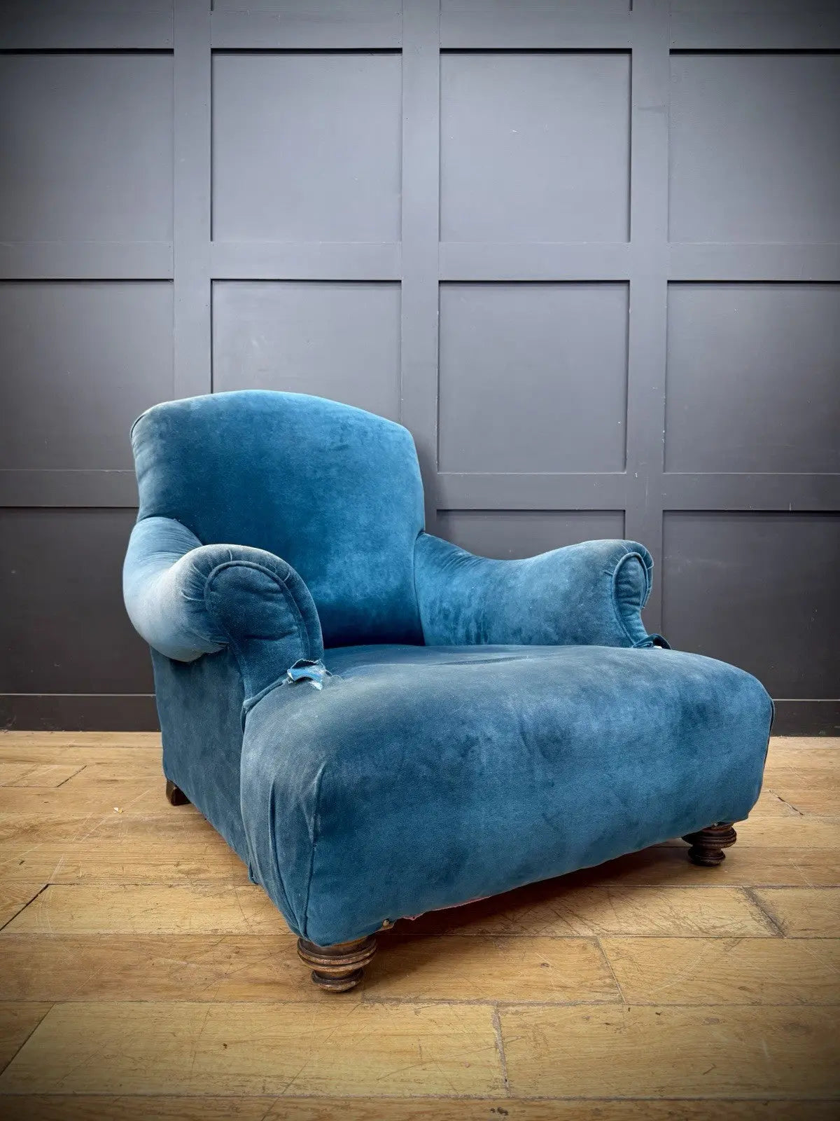 Antique blue velvet armchair with curved back, scroll arms, and stamped 'P' on frame.